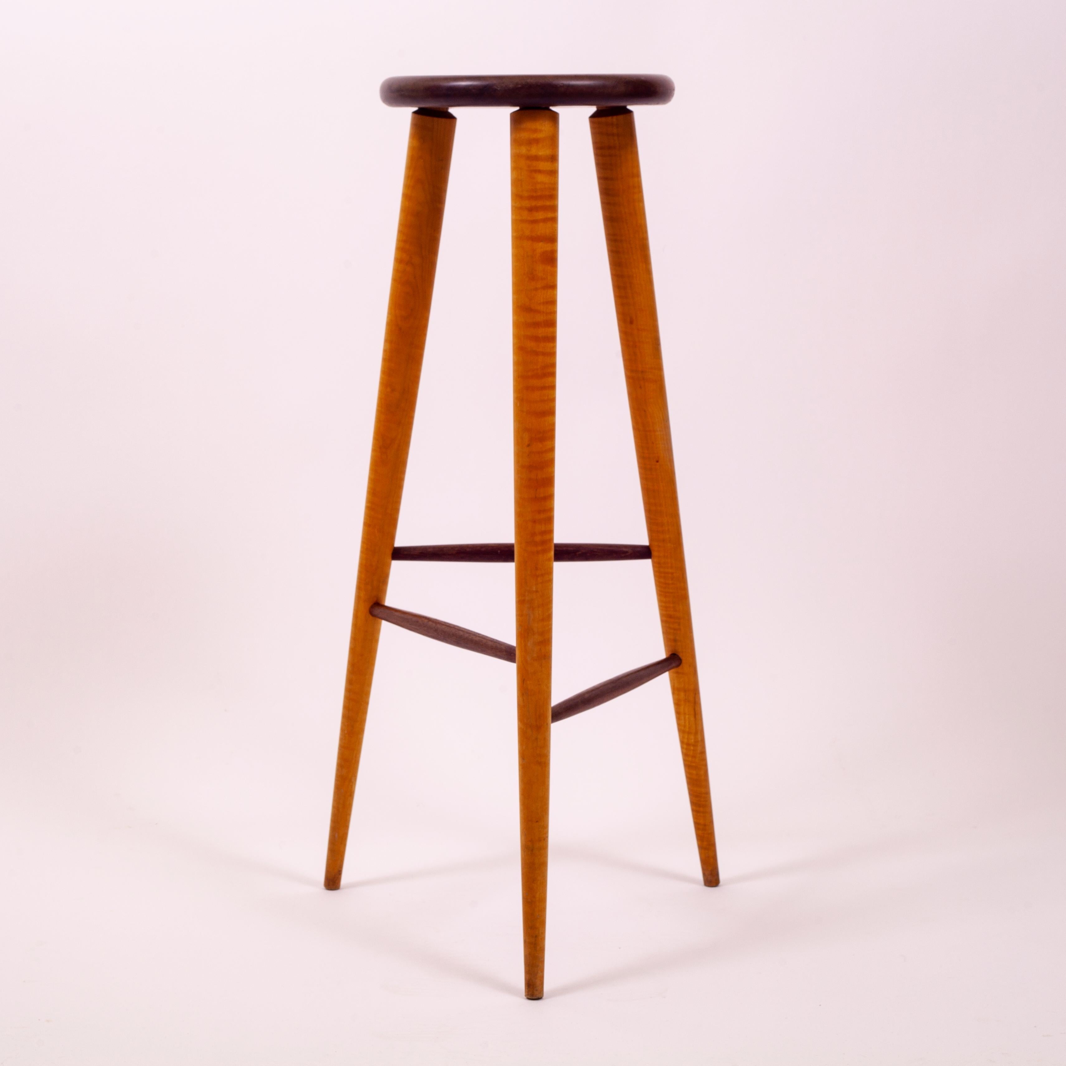 Studio stool or pedestal comprised of an artfully chosen, thick solid walnut disc atop 3 tapering legs of highly figured honey colored tiger maple. Wedged joinery and contrasting dark stretchers of varying heights make this elongated form quite