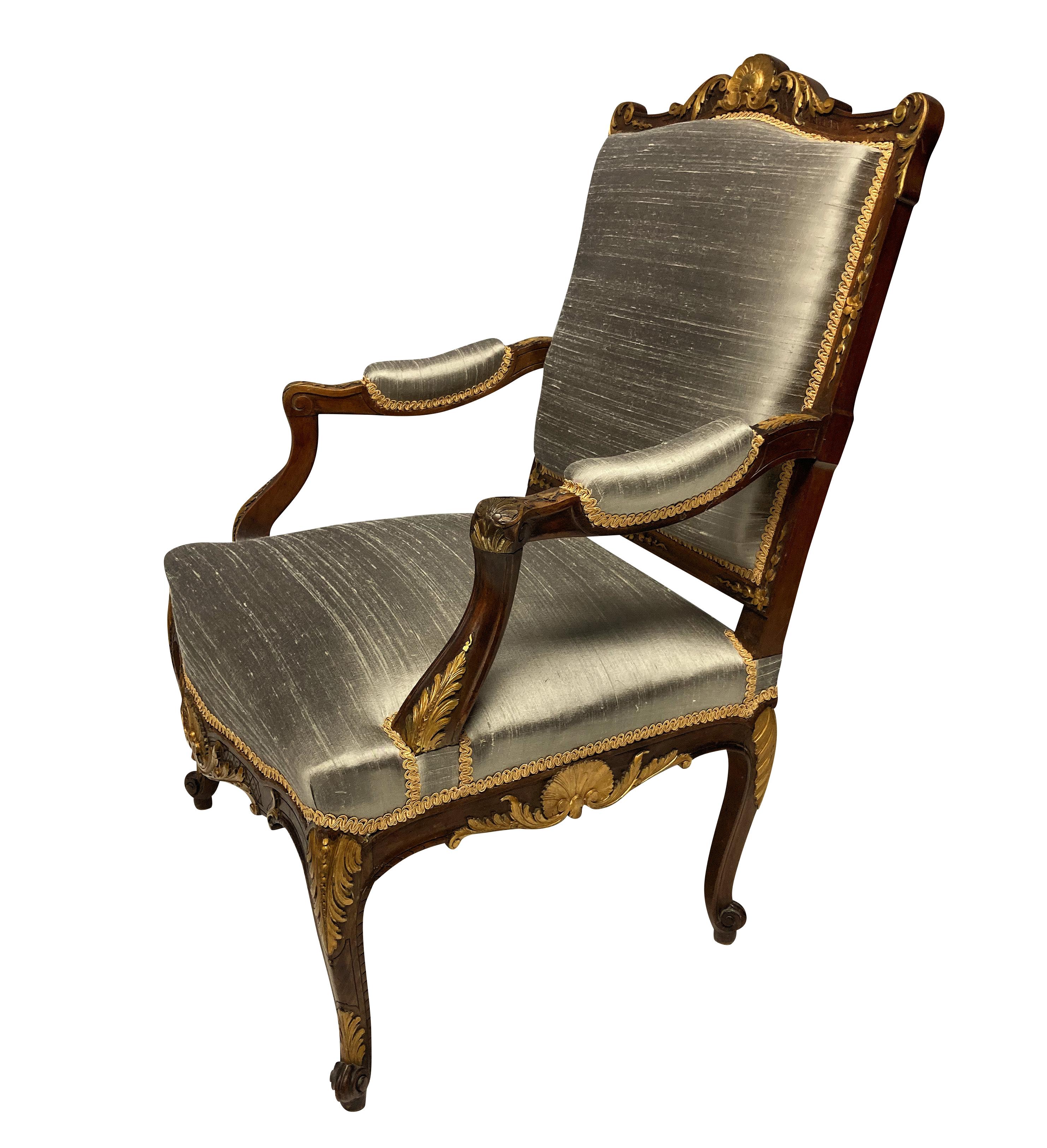 A French finely carved walnut and parcel-gilt Louis XV style armchair, newly upholstered in textured silk.