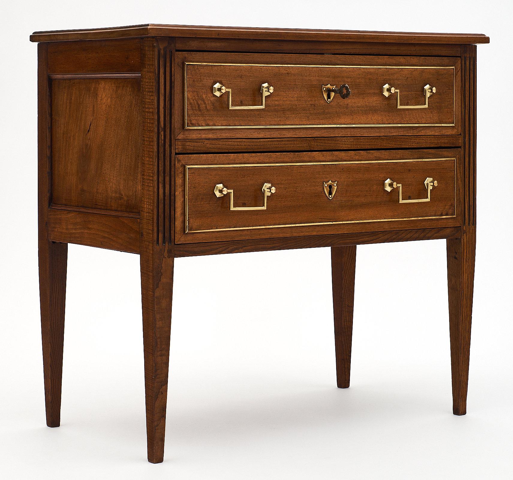 Antique walnut chest of drawers from France. This beautiful piece features two dovetailed drawers with brass hardware and trim. The tapered legs add an elegant touch to this piece, perfect as a night stand or in a bedroom.