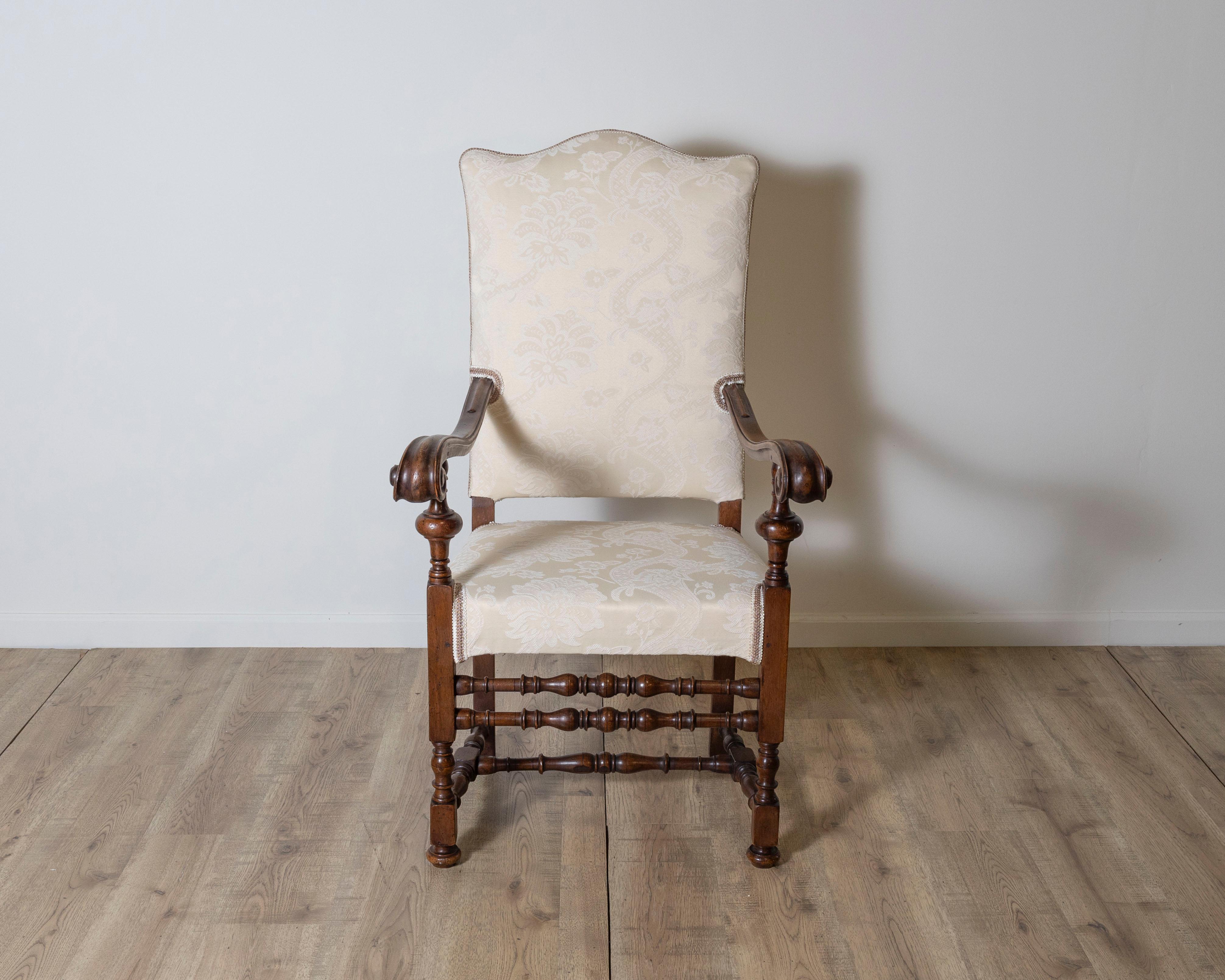 Elegante sillón de nogal del siglo XVIII procedente de la Toscana, que muestra la refinada artesanía del diseño italiano de muebles de la época. Construido en nogal macizo, el sillón presenta brazos graciosamente enrollados y patas delanteras