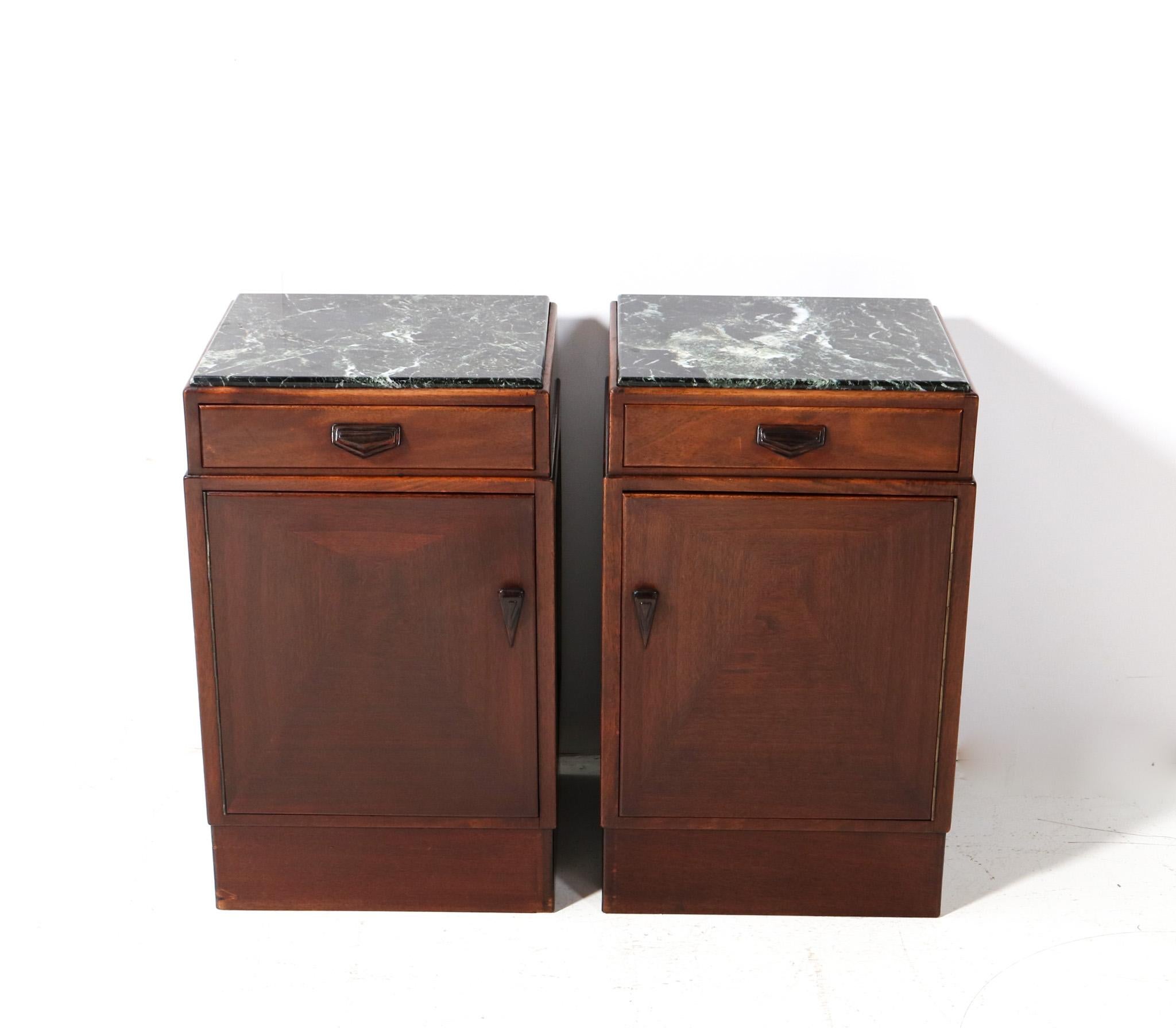 Stunning and rare pair of Art Deco Amsterdamse School bedside tables or nightstands.
Striking Dutch design from the 1920s.
Solid walnut and original walnut veneer with solid macassar ebony handles on both doors and drawers.
Original multi-colored
