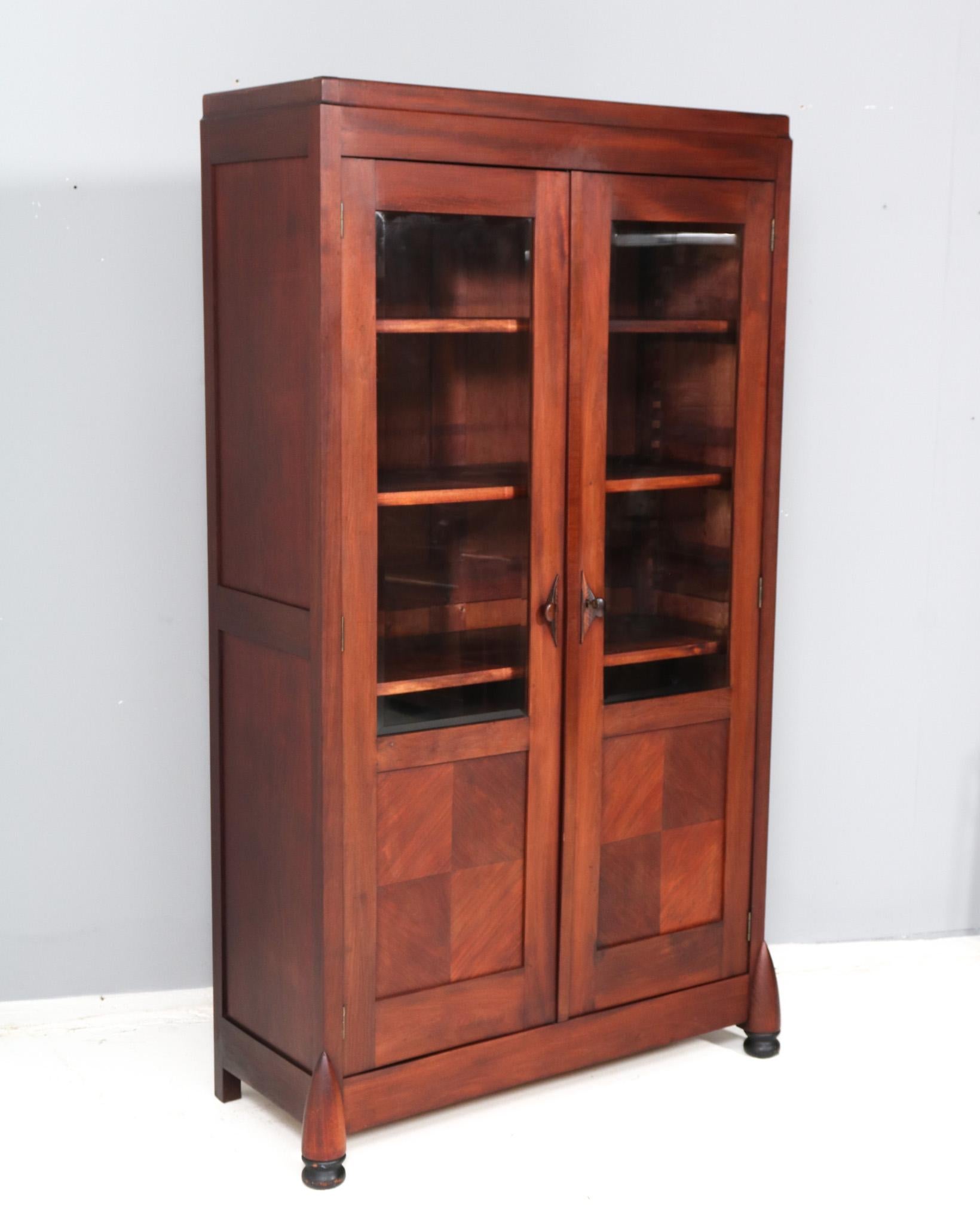 Magnificent and rare Art Deco Amsterdamse School bookcase.
Design by Max Coini Amsterdam.
Striking Dutch design from the 1920s.
Solid walnut with hand-carved decorative solid macassar ebony handles on the doors.
Both doors have also the original