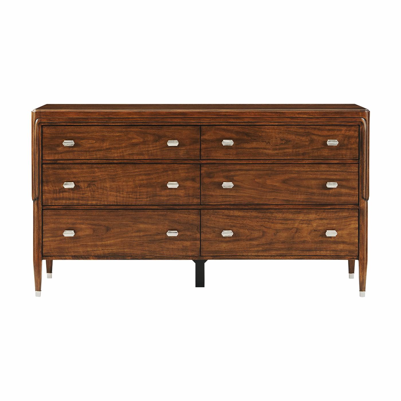 Incarnando il lusso raffinato del design dei primi del Novecento, questo comò è realizzato in squisito noce figurato, con una ricca venatura del legno che aggiunge profondità e carattere. La sua silhouette elegante è valorizzata da gambe