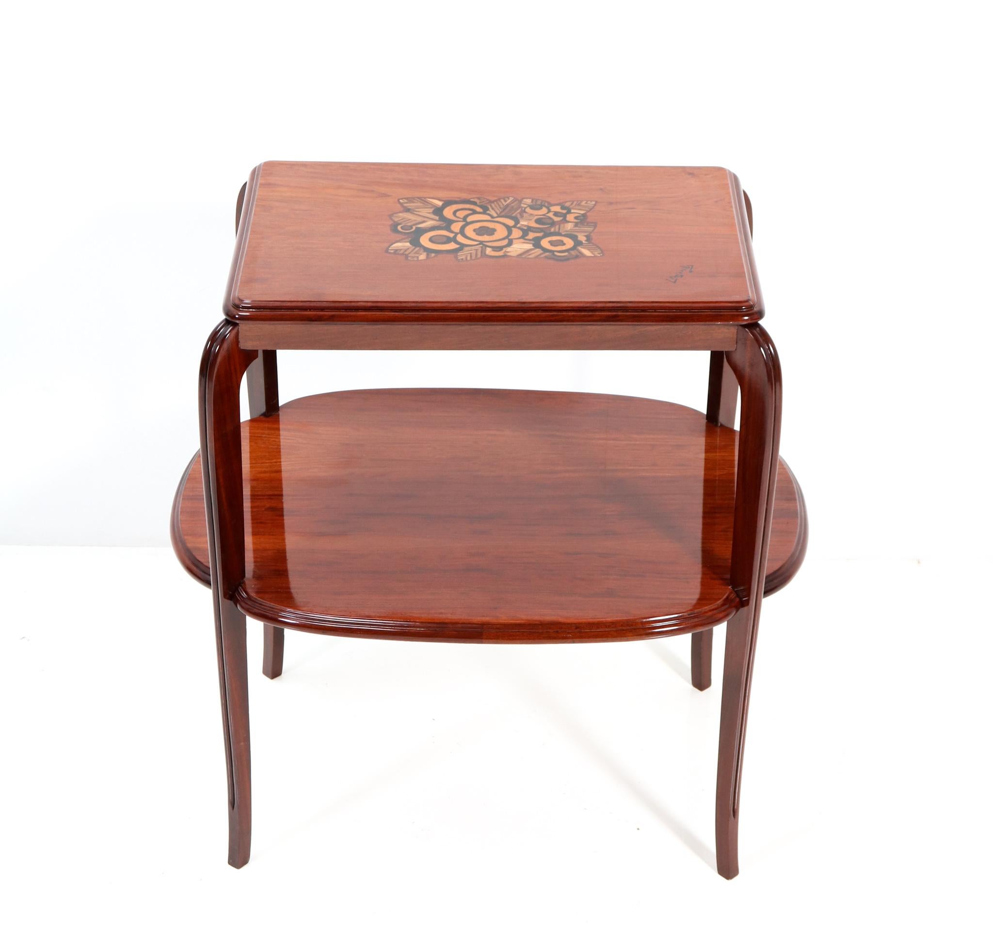 Magnificent Art Deco side table with inlay.
Design by Louis Majorelle.
Striking French design from the 1920s.
Solid walnut base with curved lined legs.
The original veneered table top is inlaid with flowers and
signature of Louis