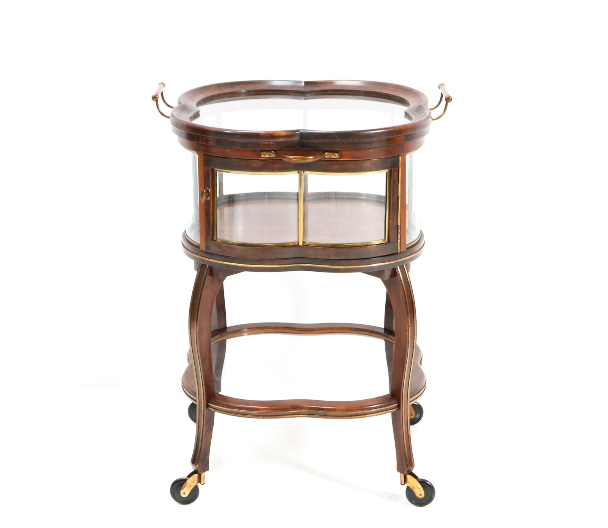 Magnificent and ultra rare Art Nouveau serving trolley or bar cart.
Striking Dutch design from the 1900s.
Solid walnut frame with original door with brass knob.
Original hand-blown curved glass panels.
The original top can be taken off and used