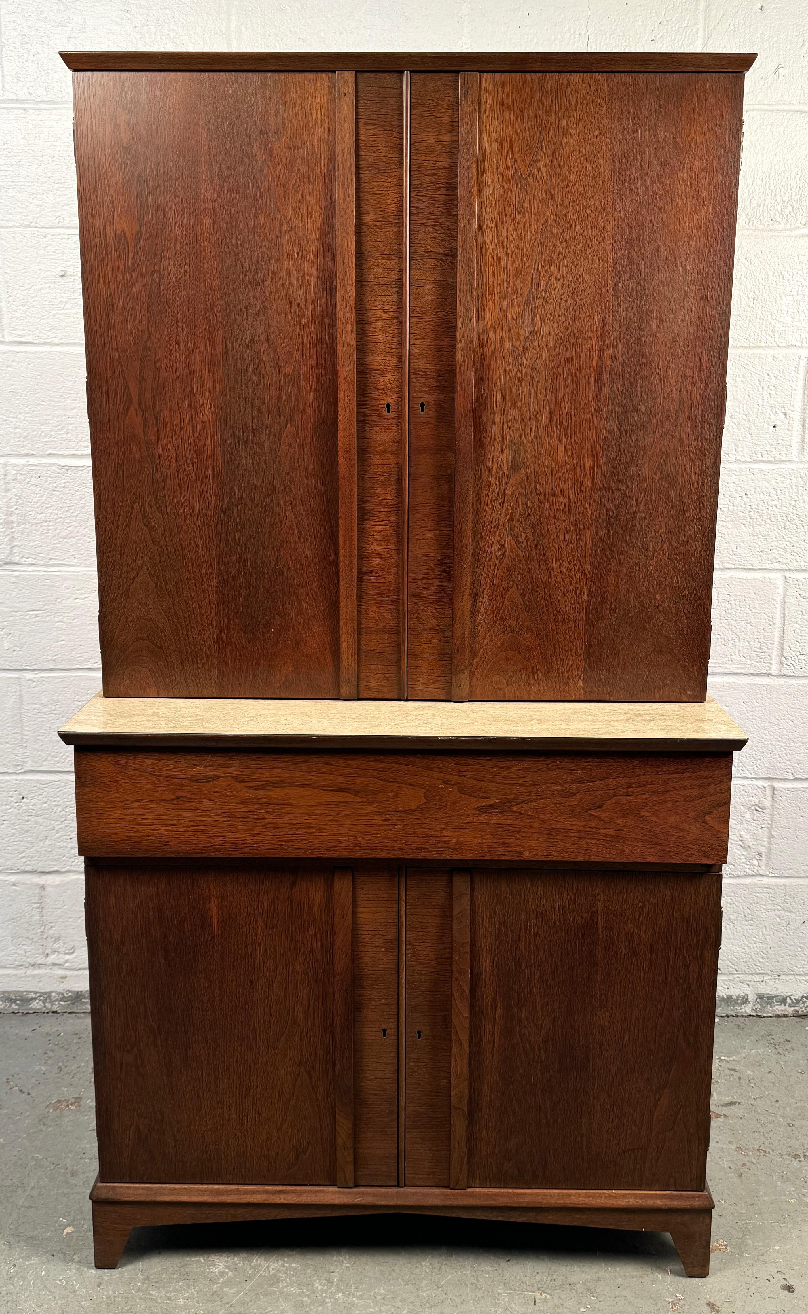 Questo elegante mobile bar americano di metà secolo è realizzato in noce con linee pulite e una calda finitura naturale. Caratterizzato da un design elegante e minimalista, si apre per rivelare un ampio spazio per bottiglie, bicchieri e articoli da