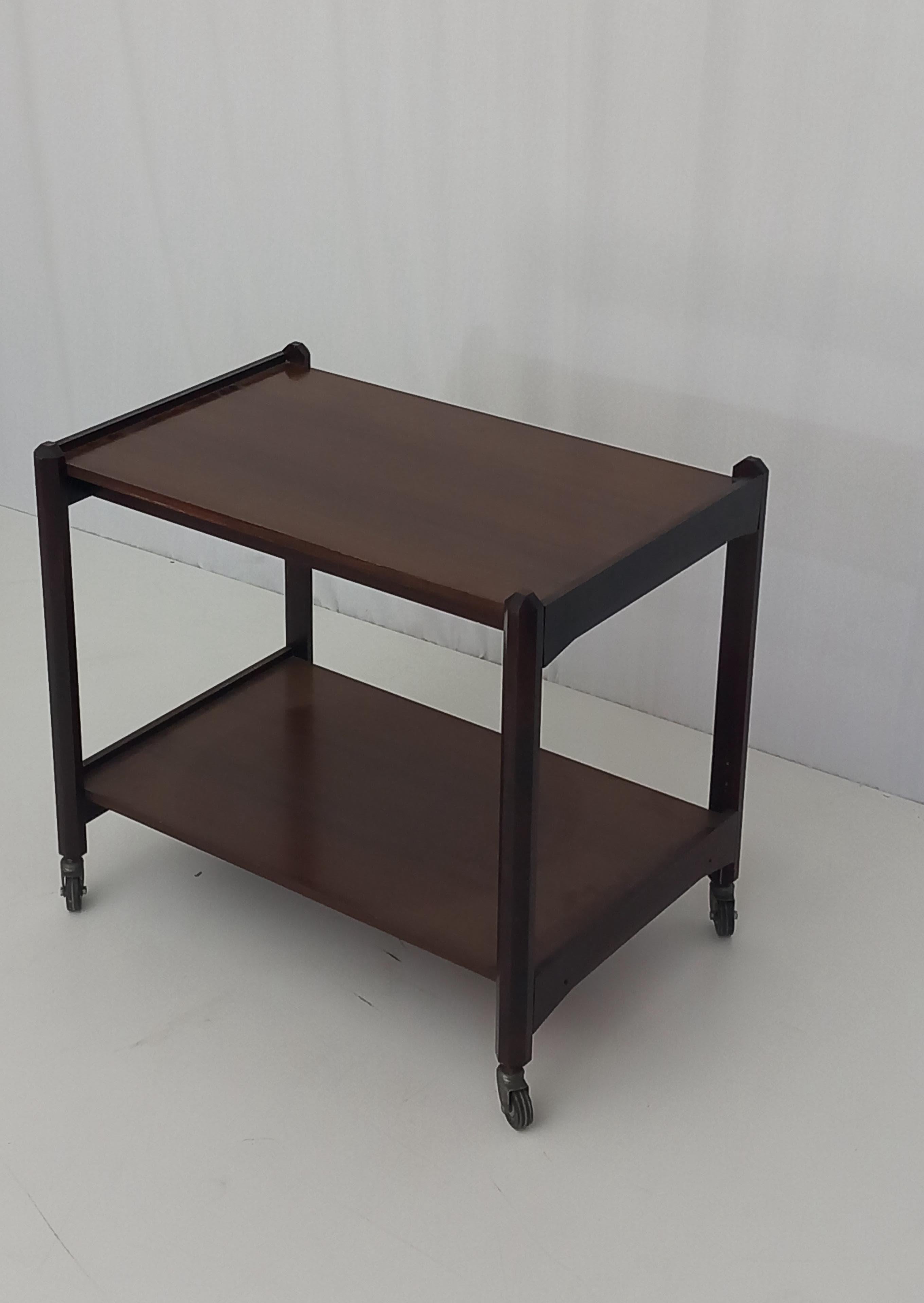 Introducing a mid-century bar cart displaying the iconic design aesthetics from the 70s. Crafted from high-quality walnut, this classic piece showcases simplicity and minimalism through its clean, simple lines. The rectangular form adds a touch of