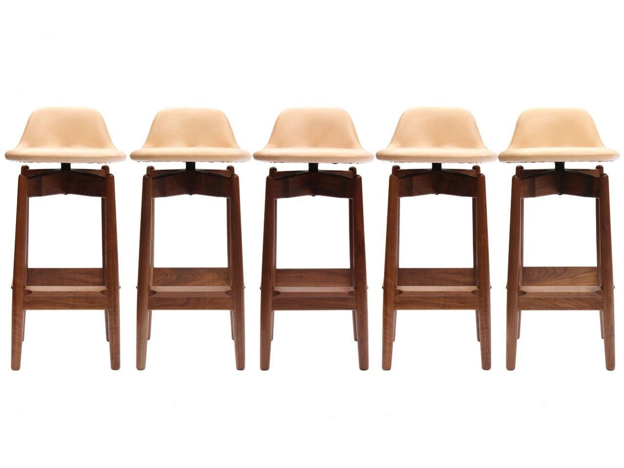 Uno sgabello da bar in teak con seduta imbottita girevole e schienale basso.