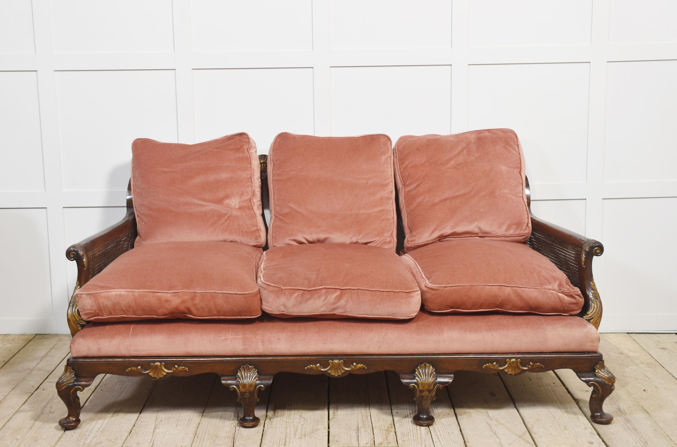 Divano a tre posti in noce Bergere, con schienale sagomato sopra tre stecche a forma di vaso intagliate a traforo, stecche decorate con decorazioni dorate a stampo, fianchi a doppia canna e braccioli a voluta. La seduta imbottita con cuscini di