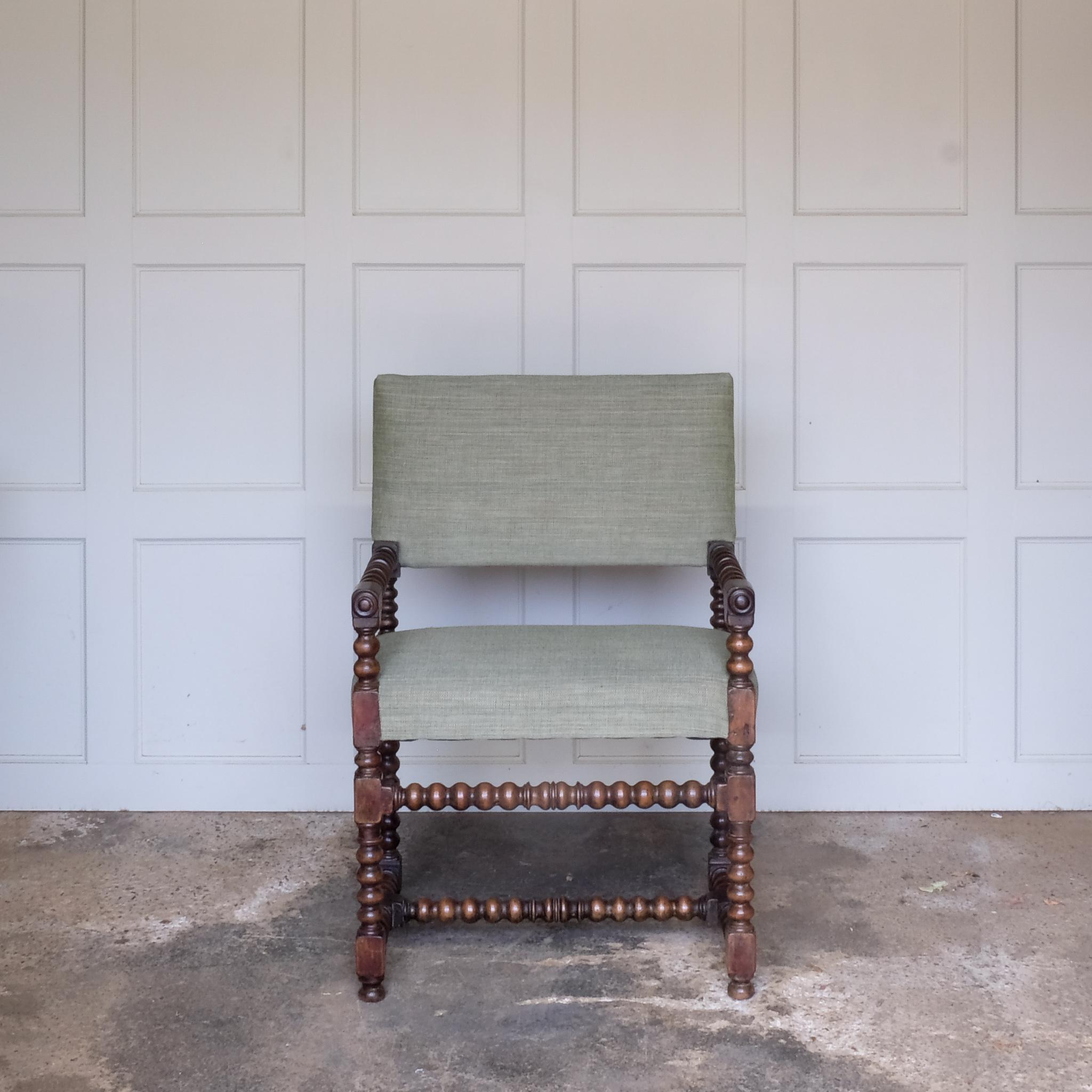 A late 17th Century walnut Bobbin turned armchair, the rectangular padded back and seat base upholstered in green Byram by Colefax and Fowler, the turned arm rests with block terminals and circular mouldings raised on turned legs and stretchers, in