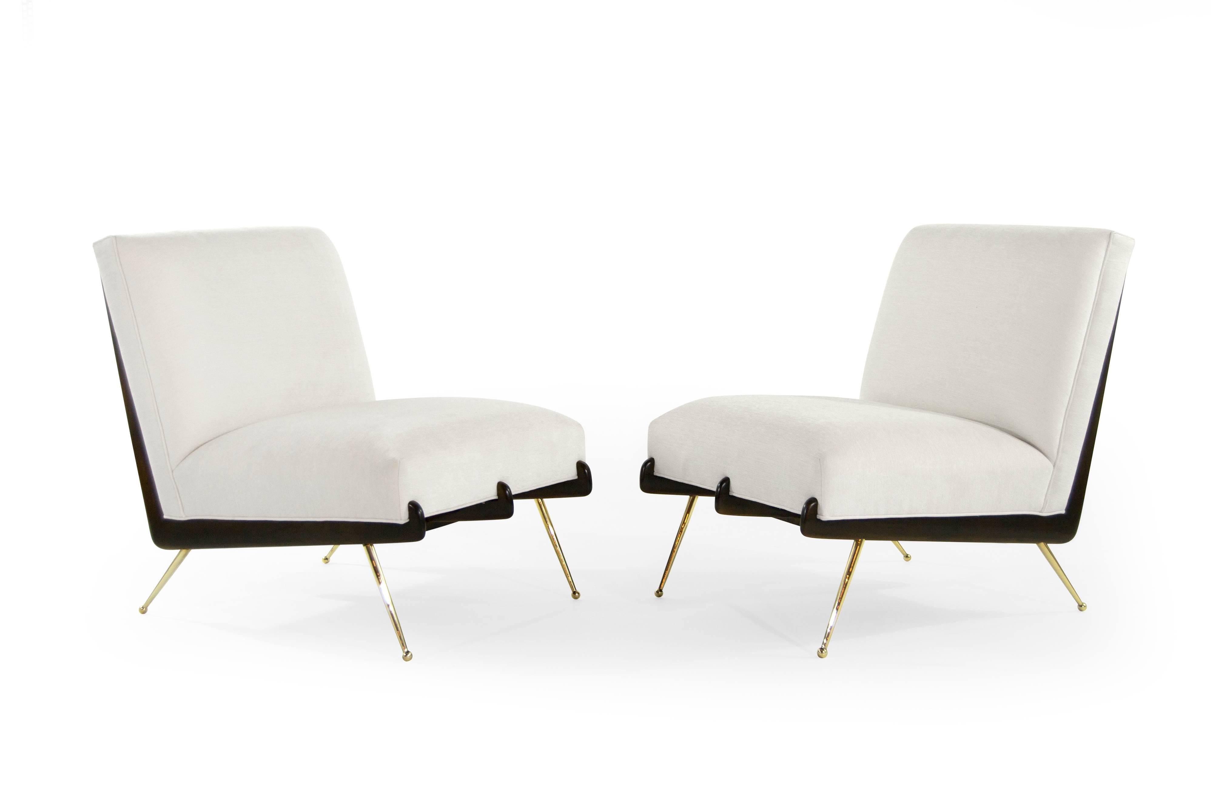 A phenomenal pair of lounge chairs in the style of Italian designer Gio Ponti, circa 1950s.

Boomerang shaped walnut frames fully restored to their original dark finish, newly upholstered in off-white velvet. Thin tapered brass legs newly