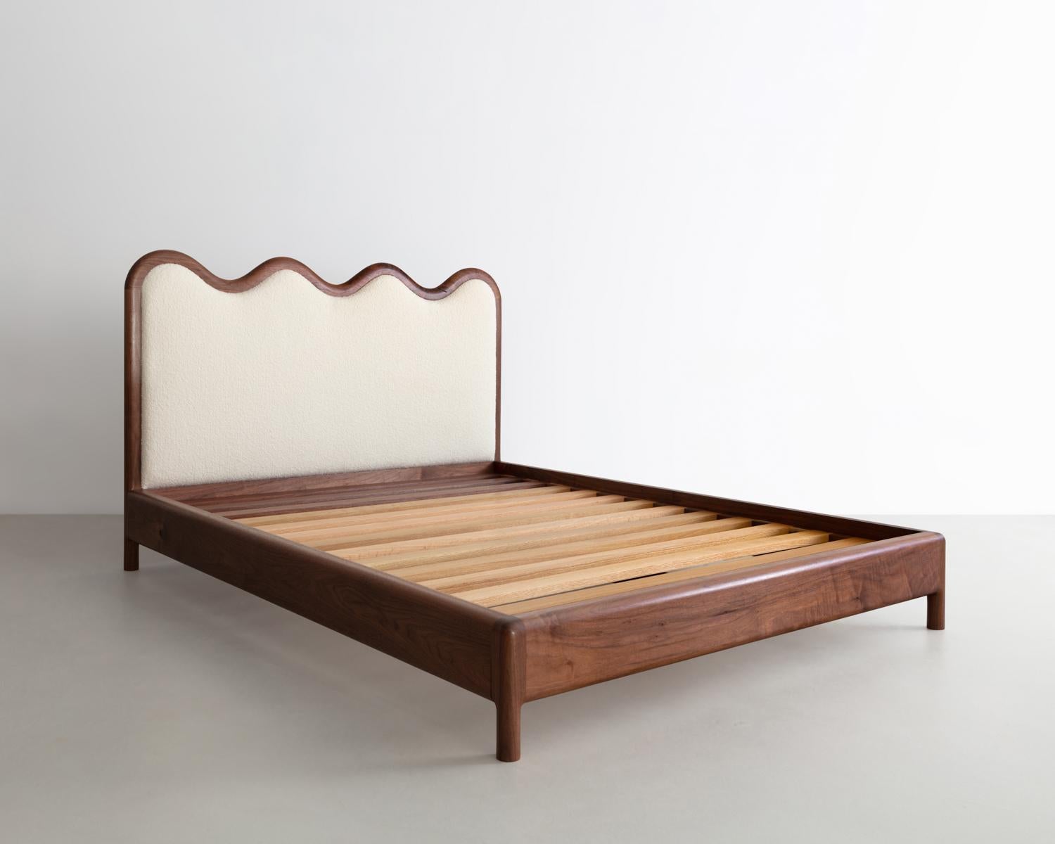 The Squiggle bed is crafted from solid Walnut, featuring a natural bouclé upholstered headboard. Solid Red Oak and walnut slats create its surface to allow for a Queen sized mattress. Each part is hand selected and sculpted to create this