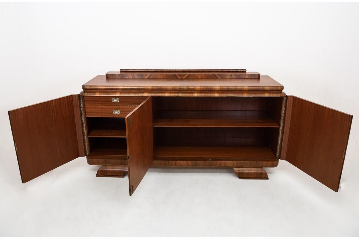 Walnut chest of drawers - buffet after renovation in the Art Deco style. A powerful chest of drawers made entirely of walnut wood. Inside, there are two drawers with metal handles and wide shelves.

Dimensions:

Height: 114cm

Width: 220cm

Depth: