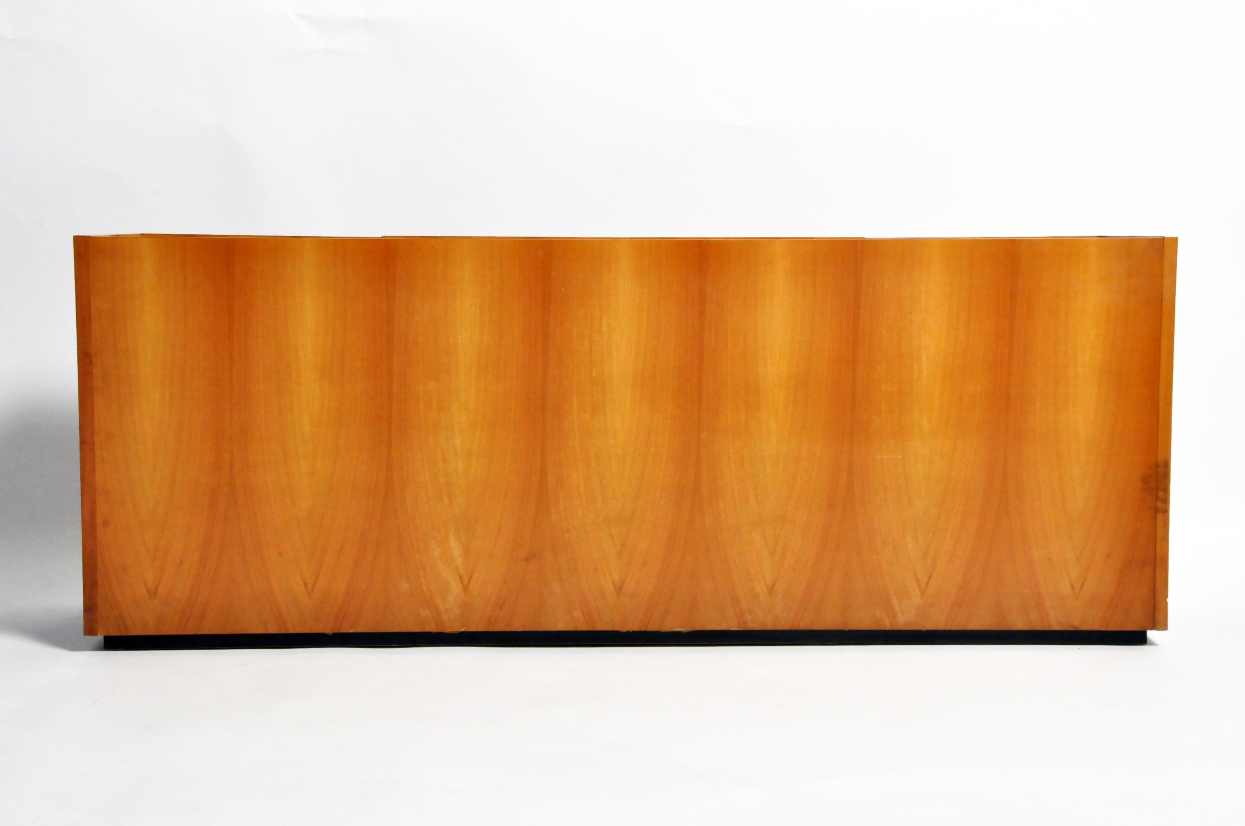 This sleek 1970s French sideboard also makes an excellent bar. The face and sides are covered in book-matched Walnut veneer with a very light stain. The end doors pivot open from the sides and feature built in shelves for holding liquor bottles. In