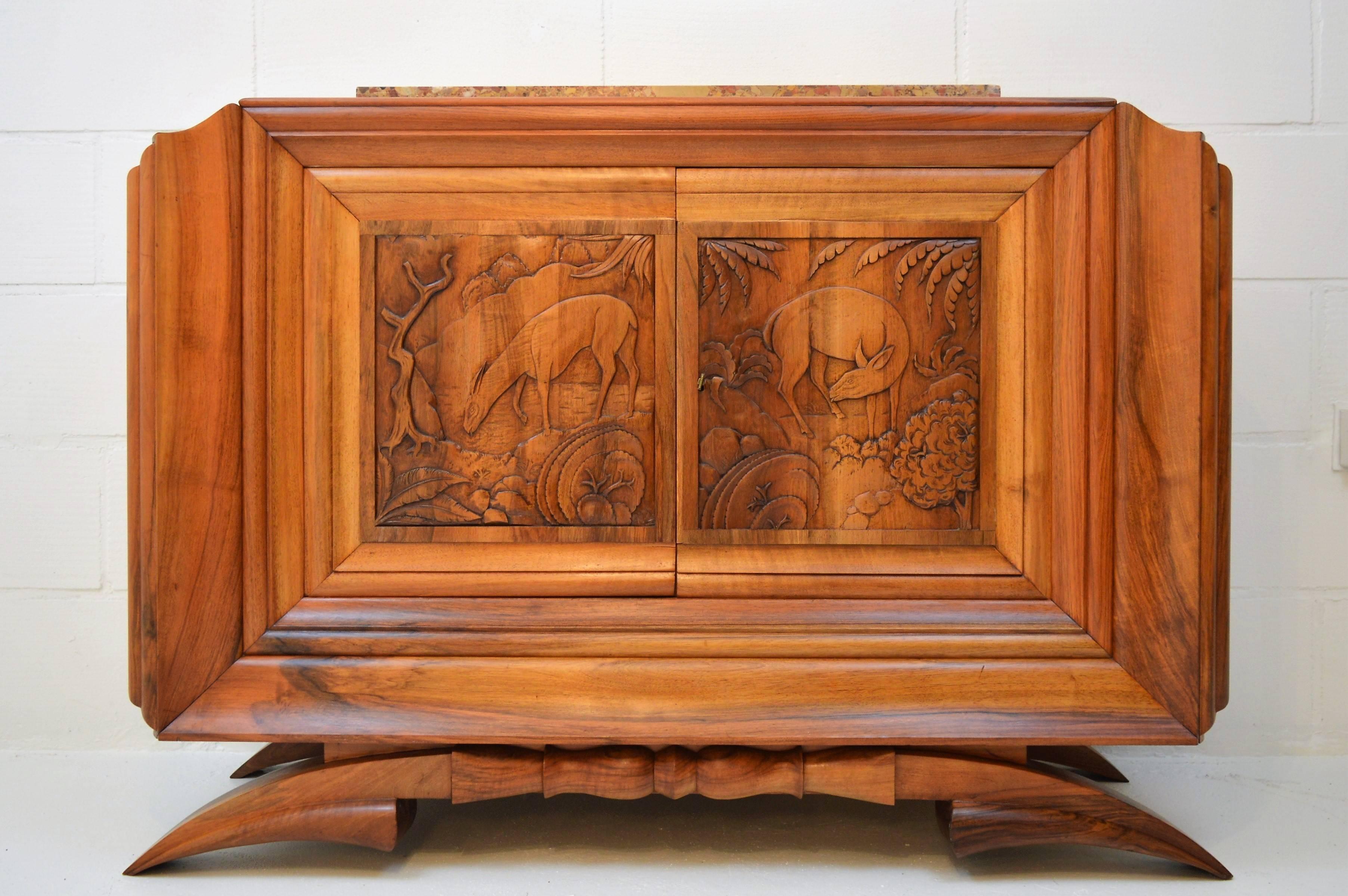 Impressive and unusual small sideboard in beautiful French walnut with sculpted doors by Dominique, Paris 1931. This sideboard is made in the style that in France is called Áfricanisme, and was very popular by several artists in the early 1930s.