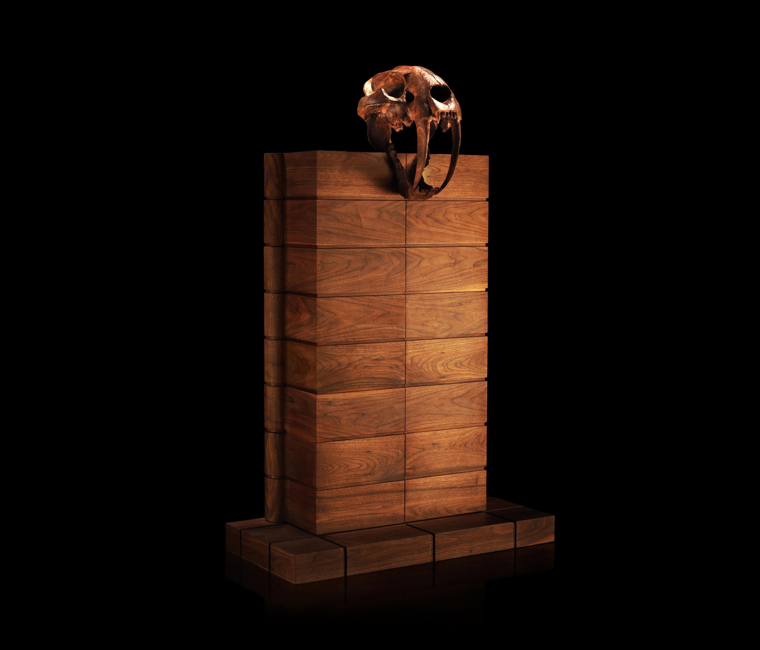 This remarkable design features a hand-carved wood sculpture of a prehistoric saber-tooth feline's skull perched on top of the cabinet, working as the handles. The cabinet is hand-crafted in solid walnut, with sets of drawers inside entirely covered