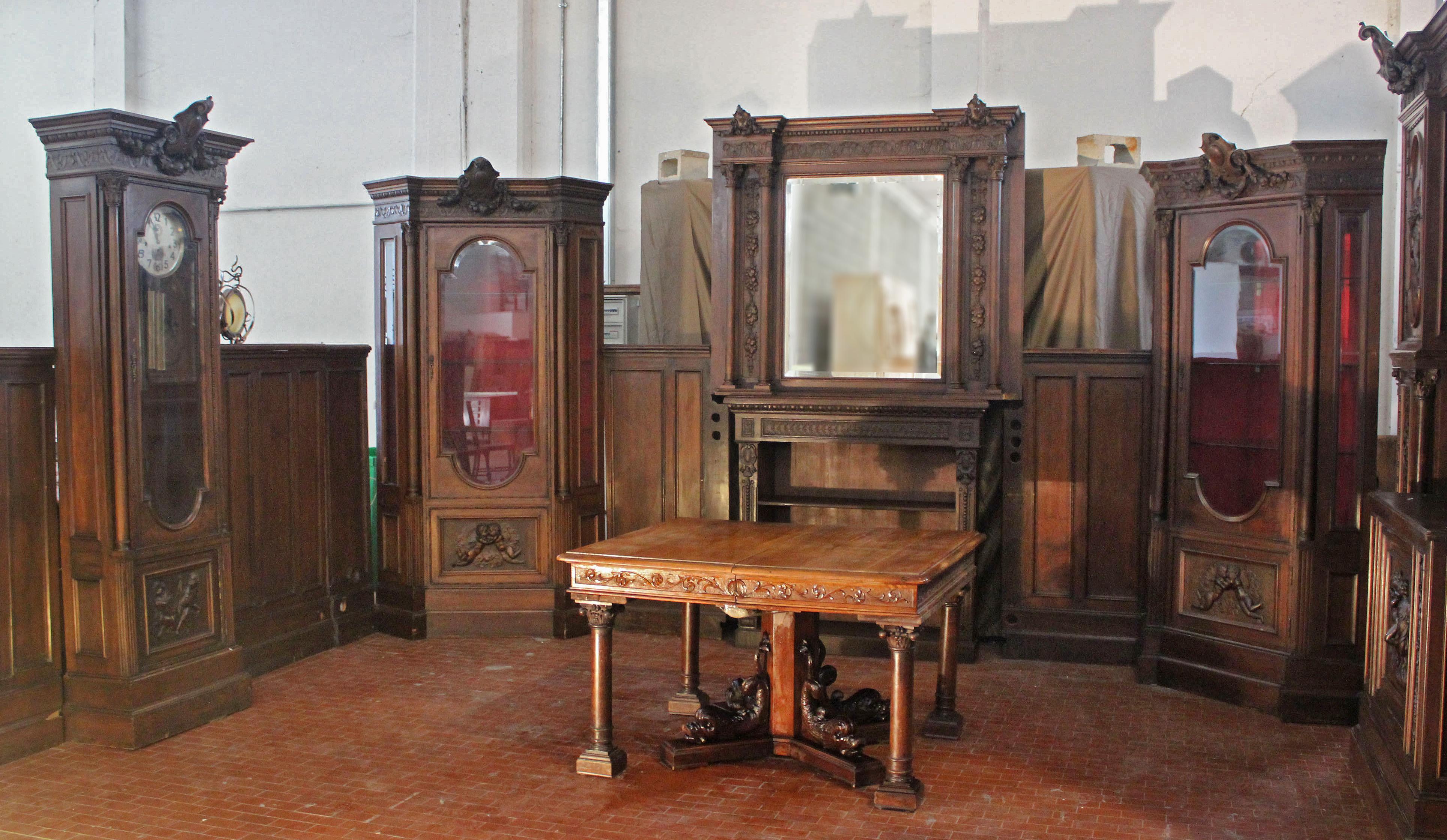 Large and important salon finely carved in walnut wood, from Genoa, which includes: Boiserie H163x700 (to be restored), 2 sideboards with riser H 293 X 247 X 70 (good condition), 2 cornerboards H 263 X 136 X 90 (good condition) 1 Clock H 263 X 80 X