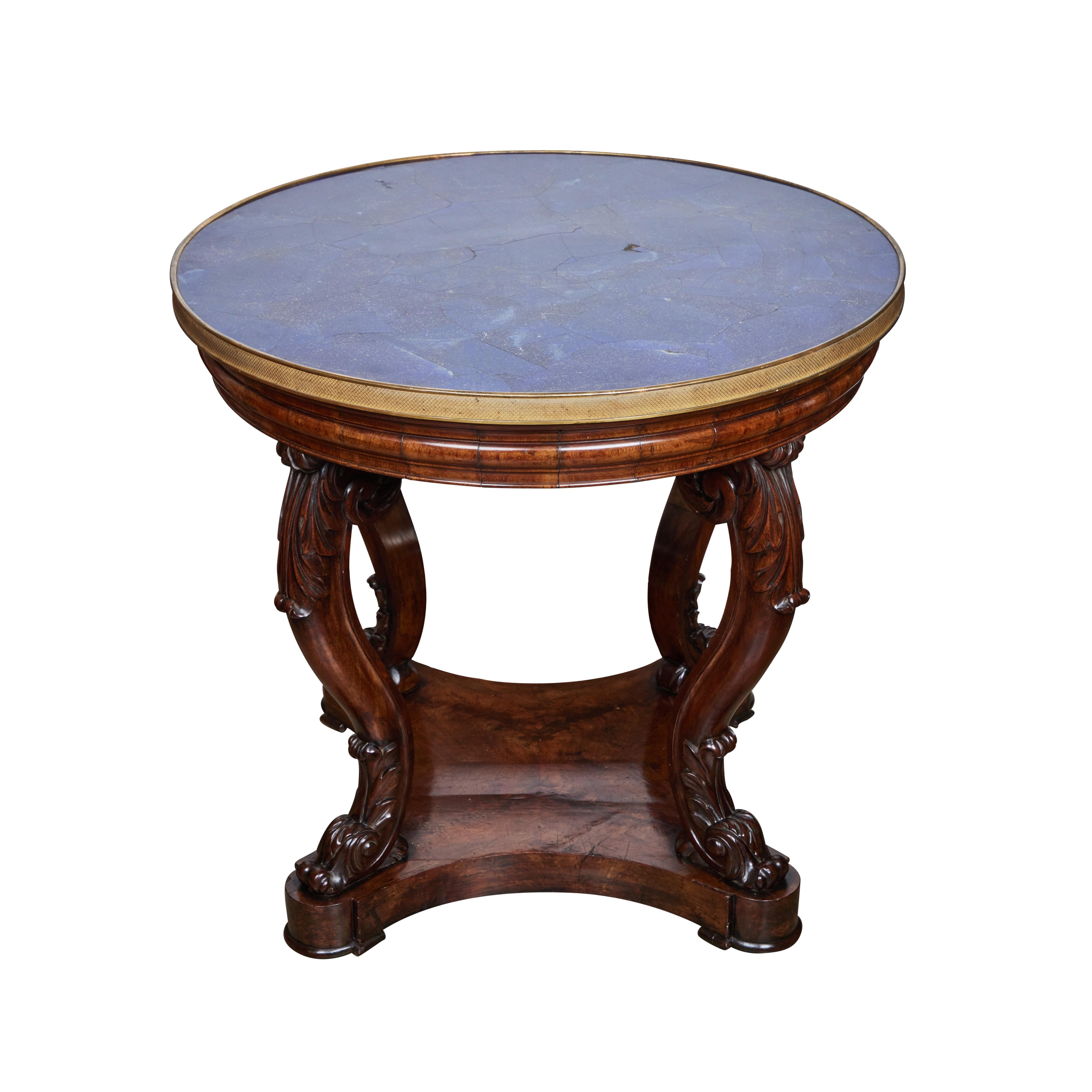 A rare, round, hand carved walnut center table with lapis veneer inlaid top surrounded by etched gilded bronze banding.