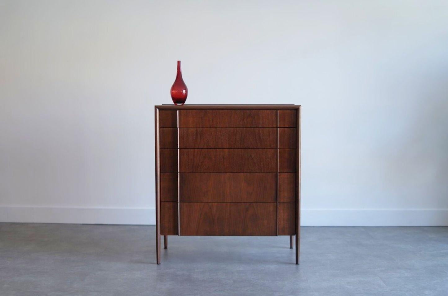 Cómoda Vintage Mid-Century Modern de Drexel, circa 1950s. Restaurada por expertos de Stamford Modern, esta pieza presenta cinco cajones que aumentan elegantemente de tamaño, ofreciendo un amplio espacio de almacenamiento. Las caras esculpidas de los