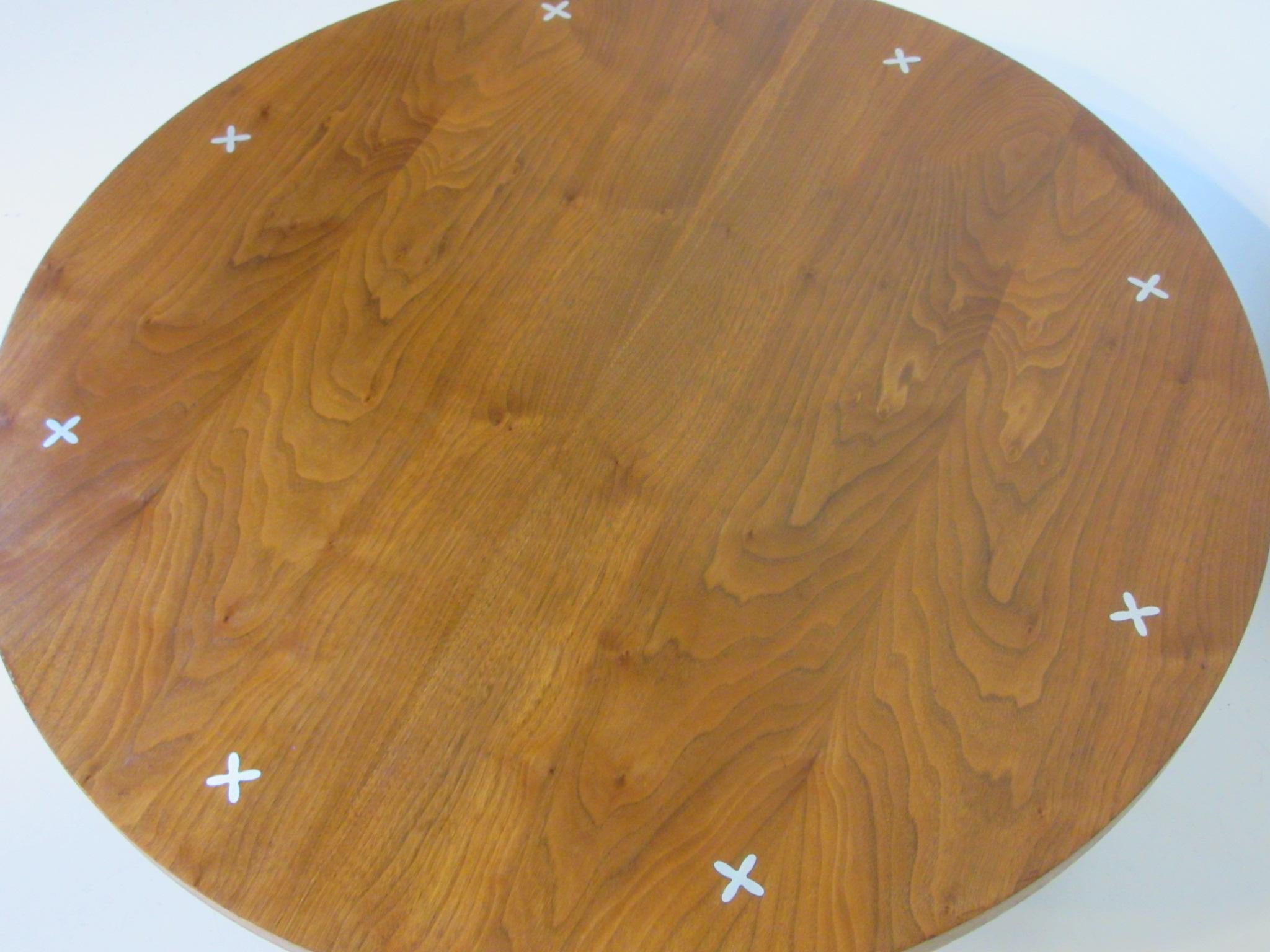 A very well grained round walnut coffee table with inlaid aluminum X patterns and nice rounded conical legs manufactured by American of Martinsville model # 3757. The flamed pattern of the wood top is just fantastic.