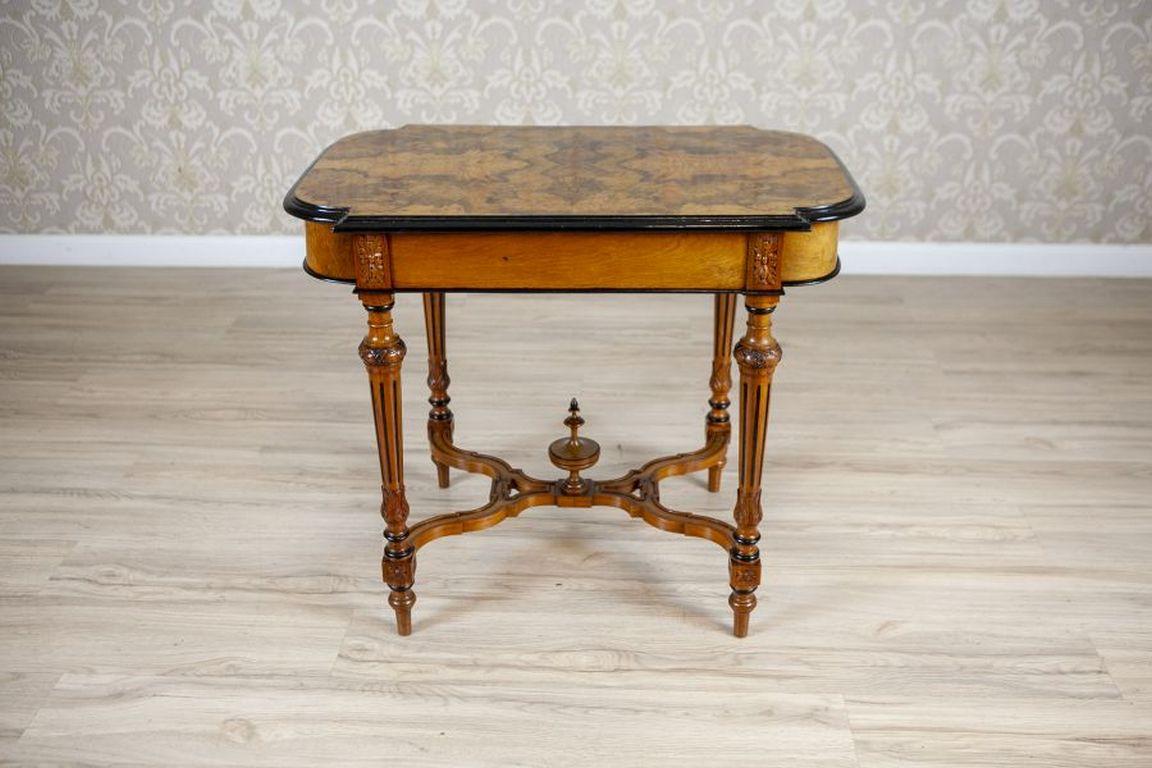 Walnut Coffee Table From the Late 19th Century

A small table made of walnut wood, with a walnut veneer top featuring a beautiful pattern. The table's top has rounded corners and a wavy profiled edge, supported by four straight legs, connected with
