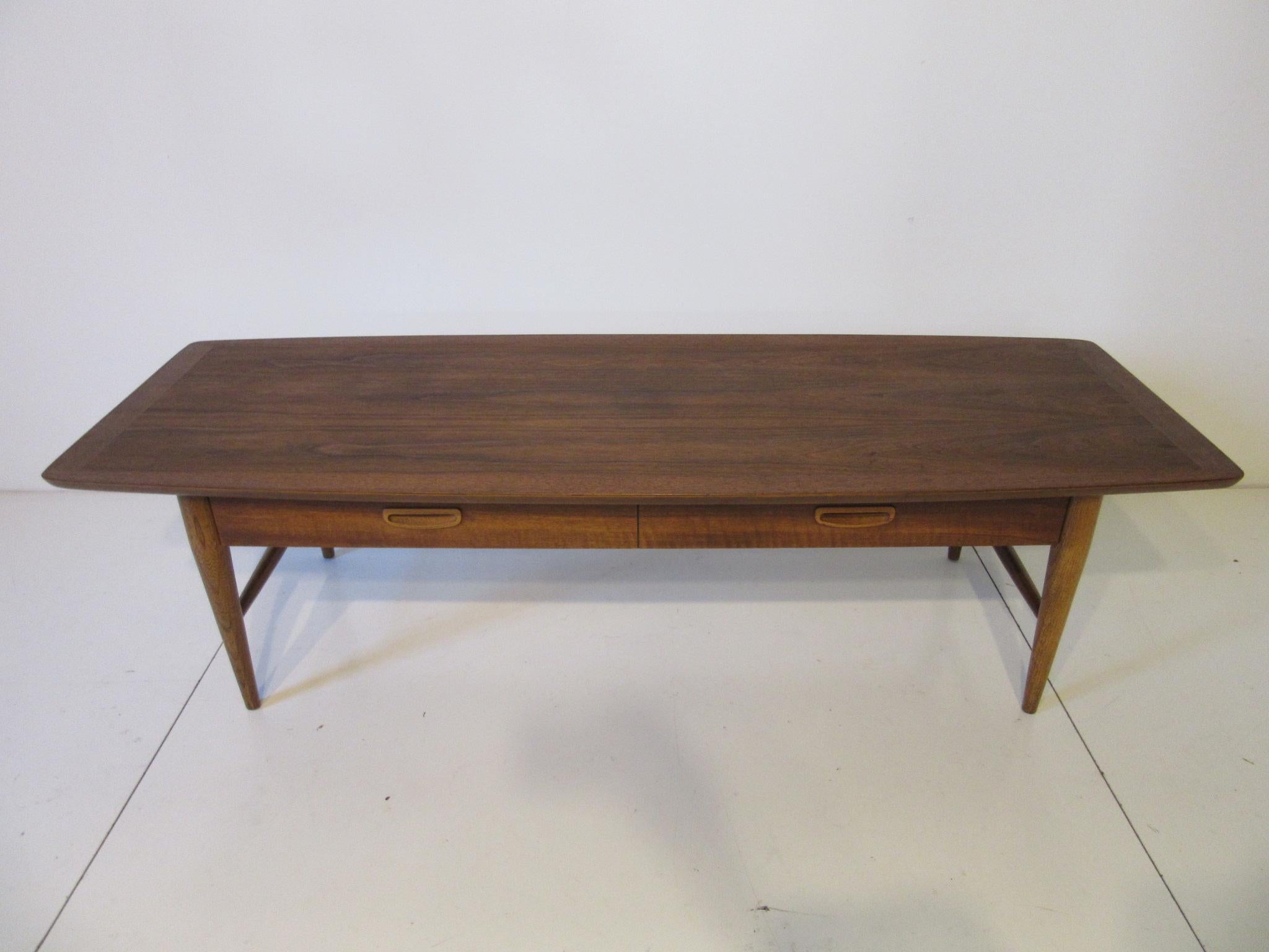 A beautifully grained medium walnut coffee table with lower single drawer manufactured by the Lane furniture company.