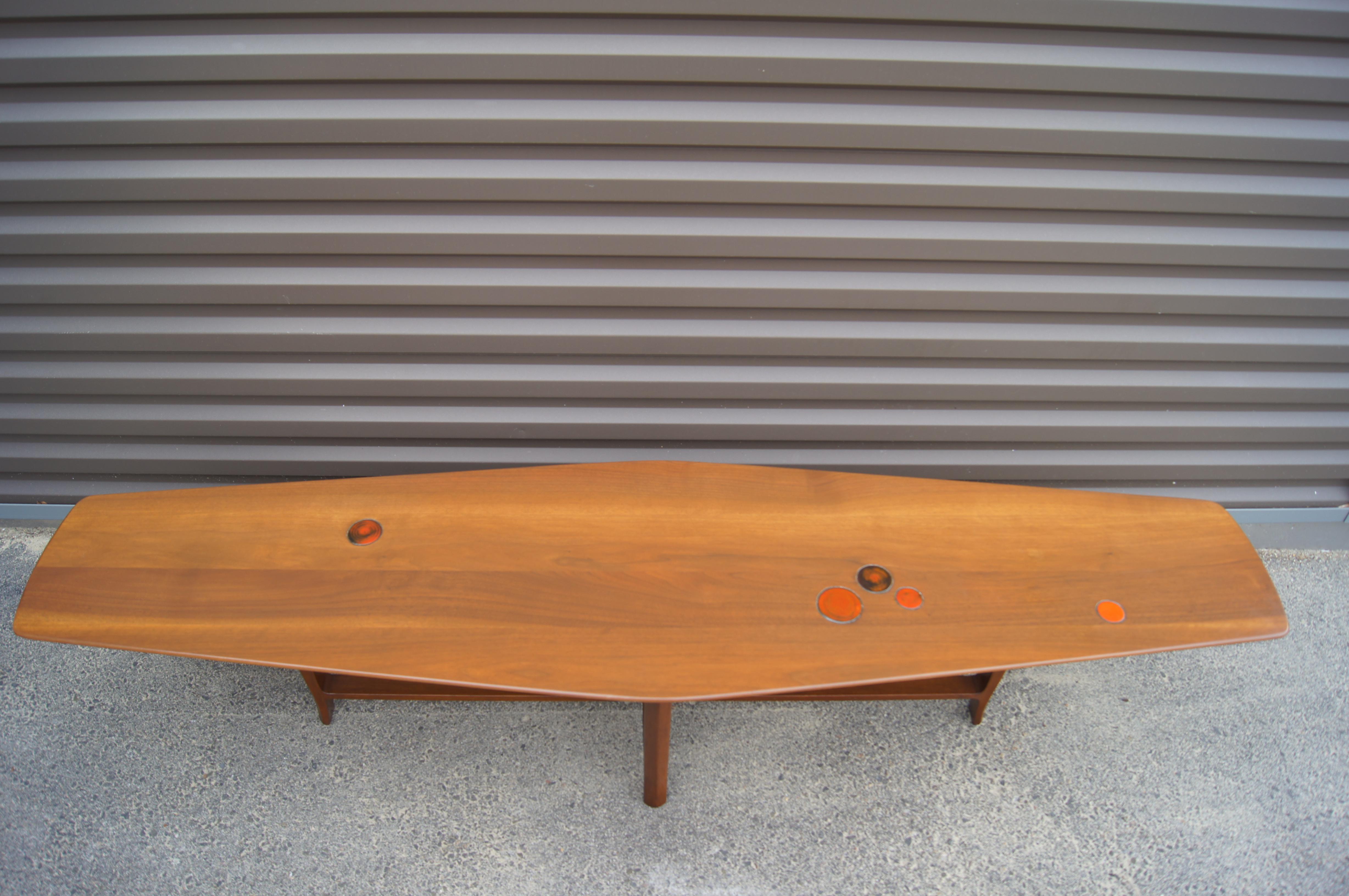 Edward Wormley designed this fabulous walnut coffee table, model 5632N, for Dunbar circa 1957. The long, angular top is inset with orange and black ceramic tiles by Gertrud and Otto Natzler and floats over a cross-frame base with a darker,