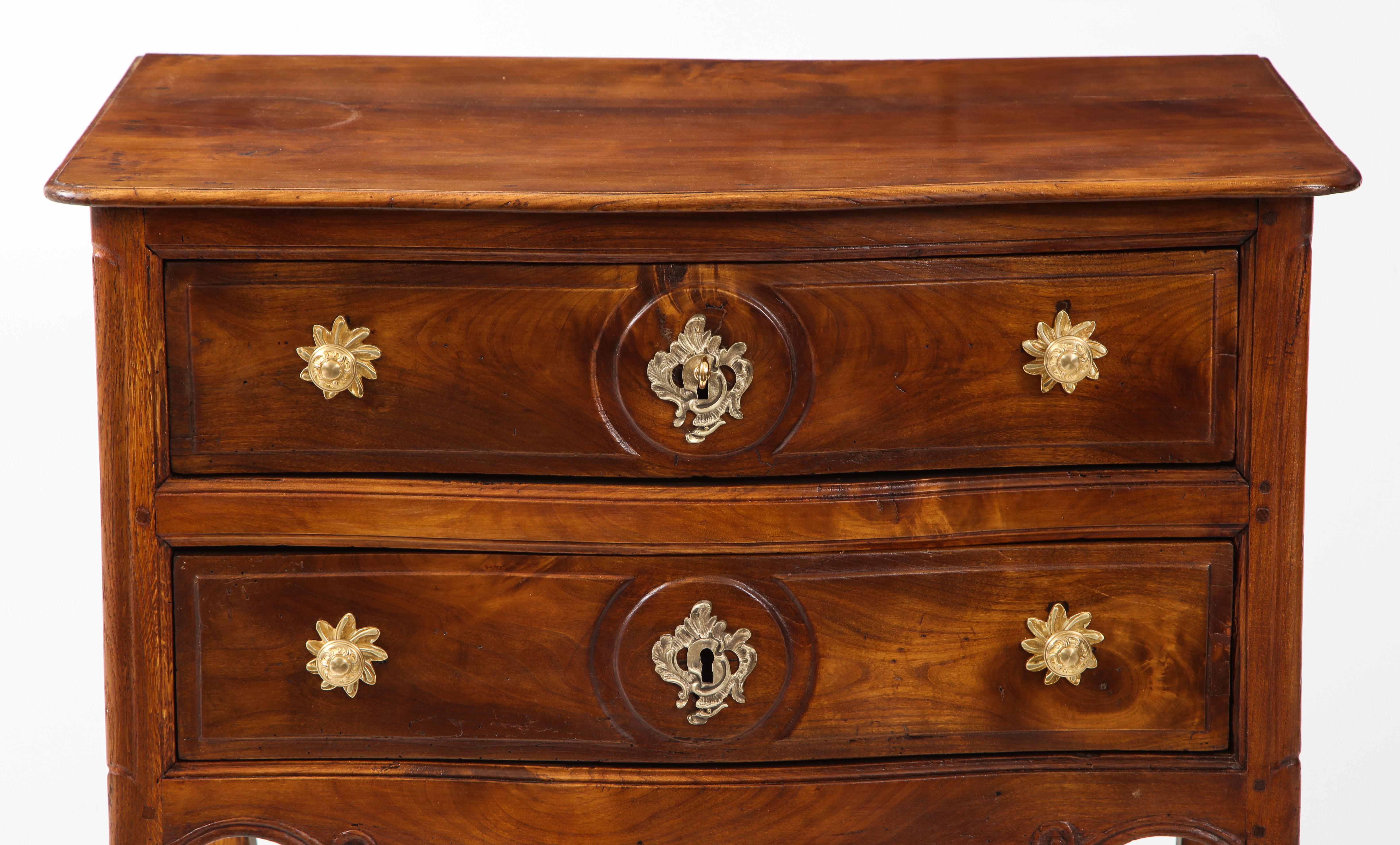This little walnut commode oozes with elegance and charm. This sweet piece in solid walnut is from the Louis XV period, circa 1750. If features two drawers with original gilt bronze hardware and a scalloped apron, raised on cabriole legs. Its small