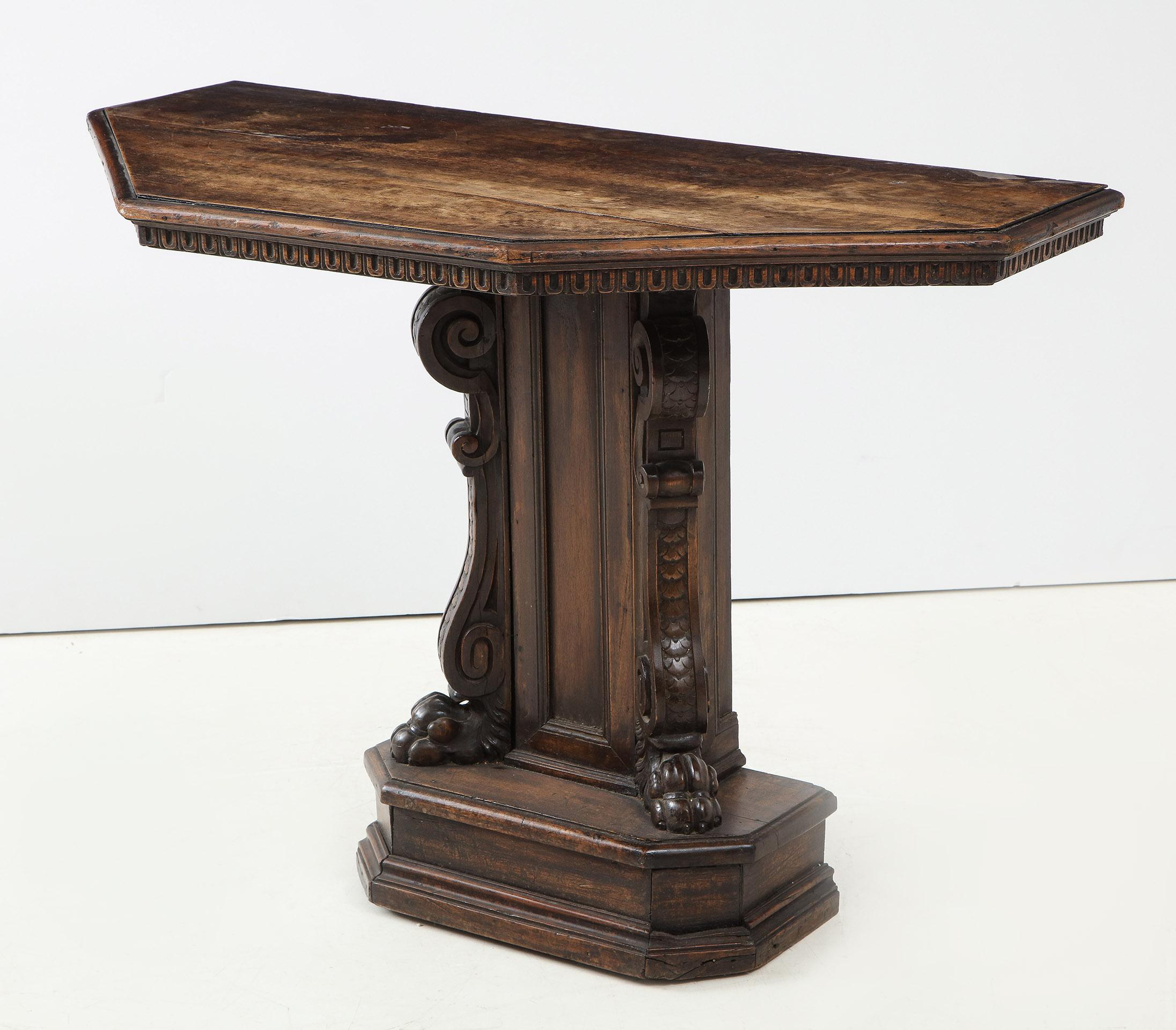 Renaissance Revival walnut console table

The canted corner top with a dental molded frieze over a central column with a well carved scroll ending in paw feet, the whole on a stepped plinth.