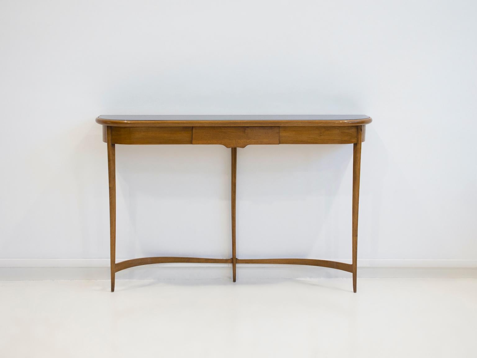 Console table of lacquered walnut wood with dark stained glass top. Designed by Carlo Enrico Rava in the 1950's. The console has one drawer, rounded edges and stands on three legs.