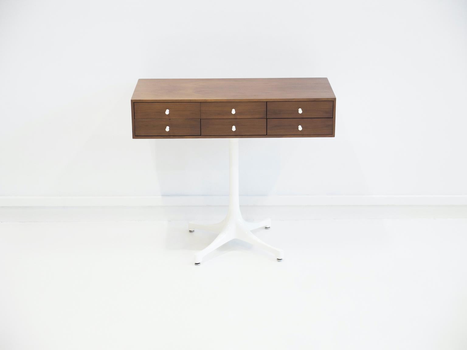 Small chest of drawers or console table in walnut, design attributed to George Nelson. Base made of white lacquered metal with a star base, box-shaped body with surfaces made of walnut. Equipped with six drawers, fittings made of white lacquered