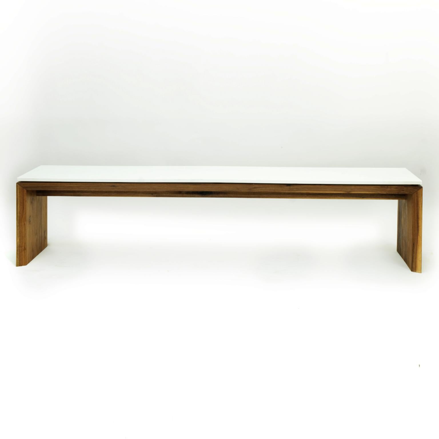 This bench is composed of a Corian top floating on an elegantly detailed walnut frame. It is large enough for one's imagination or a group conversation. Spanning 7' long, it commands environments while subtly disappearing like its double miter