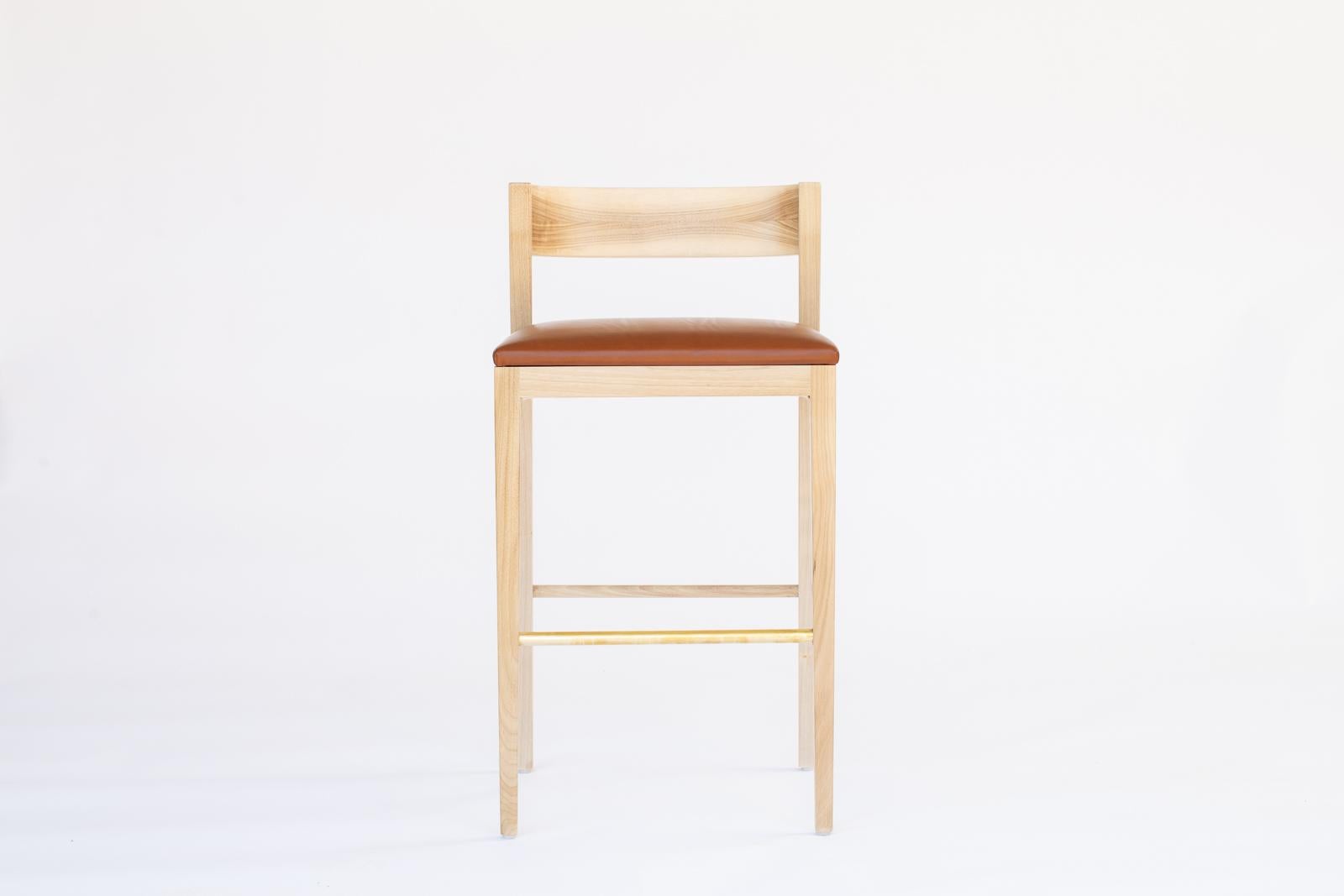 A tailored counter stool inspired by the Bahaus movement of the 1920s. This refined stool has a Minimalist flair, with its refined tapered legs and distinctive back support. Custom sizes and finishes available.