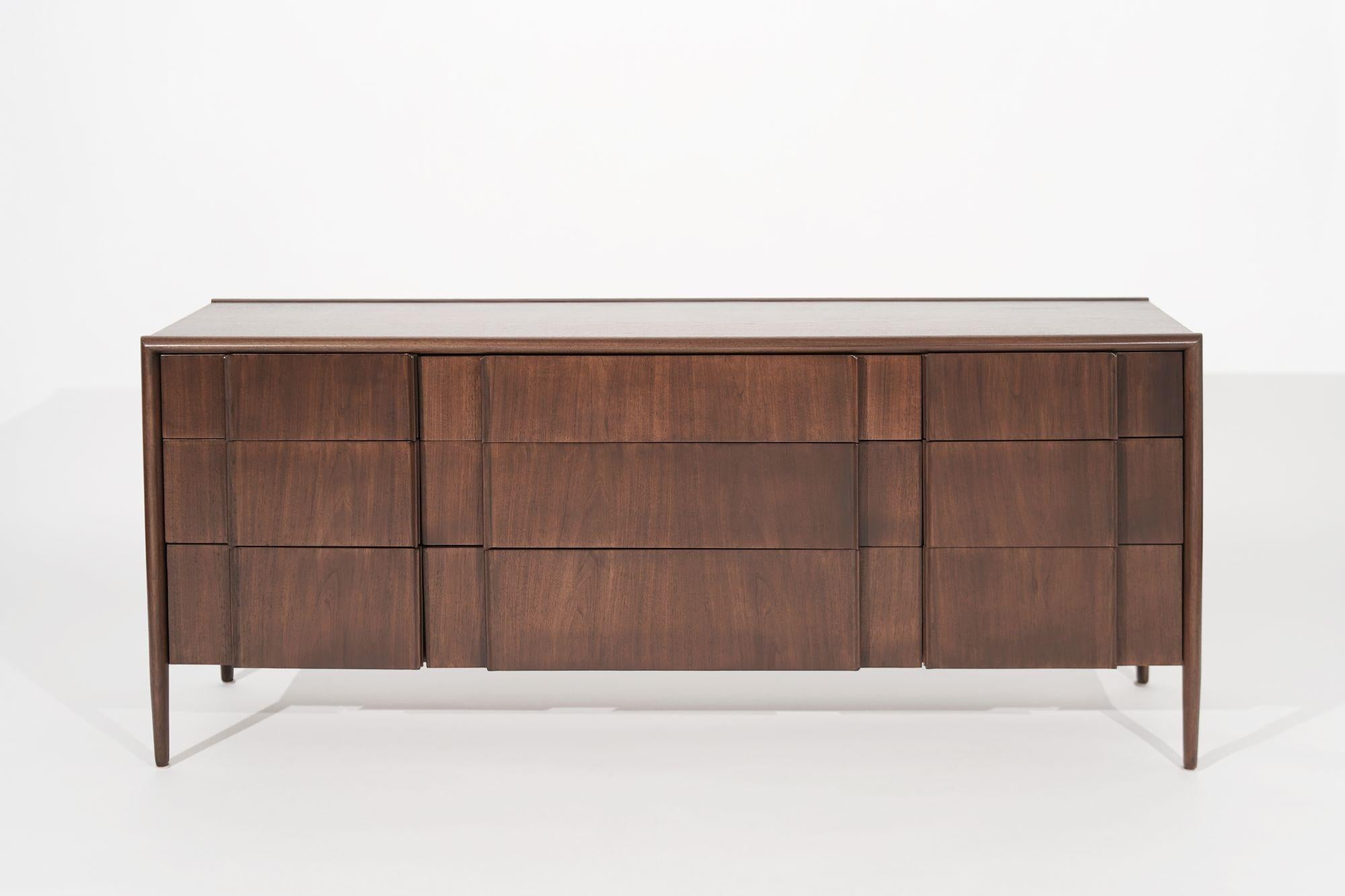 A dresser executed in walnut by Drexel Furniture, circa 1950-1959. An all-around very handsome design featuring Dual drawers with wood drawer pulls. Completely restored by the professional team of Stamford Modern. 
 
Other designers from this era