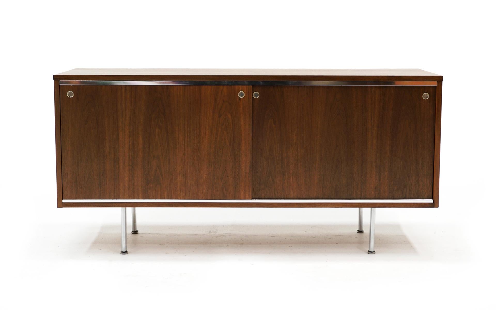 George Nelson for Herman Miller credenza / sideboard / storage / media cabinet. Expertly refinished. Walnut case with walnut sliding doors revealing storage space with an adjustable shelf. The width of the openings makes this ideal for media