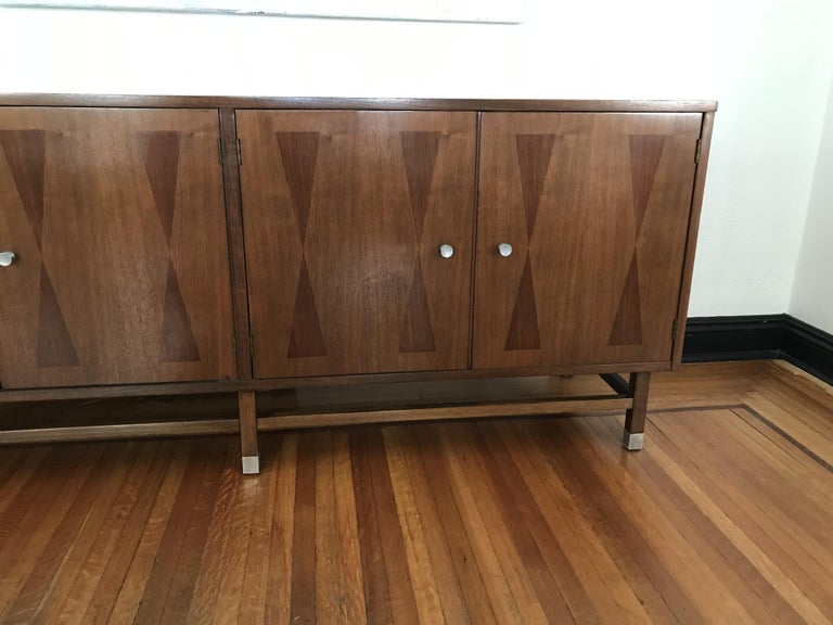 Walnut credenza made by Stanley manufacture.
The doors wood feature 2 isosceles triangles inlays. The left doors open on one shelf and the right ones 3 drawers
The hardware is silvered.