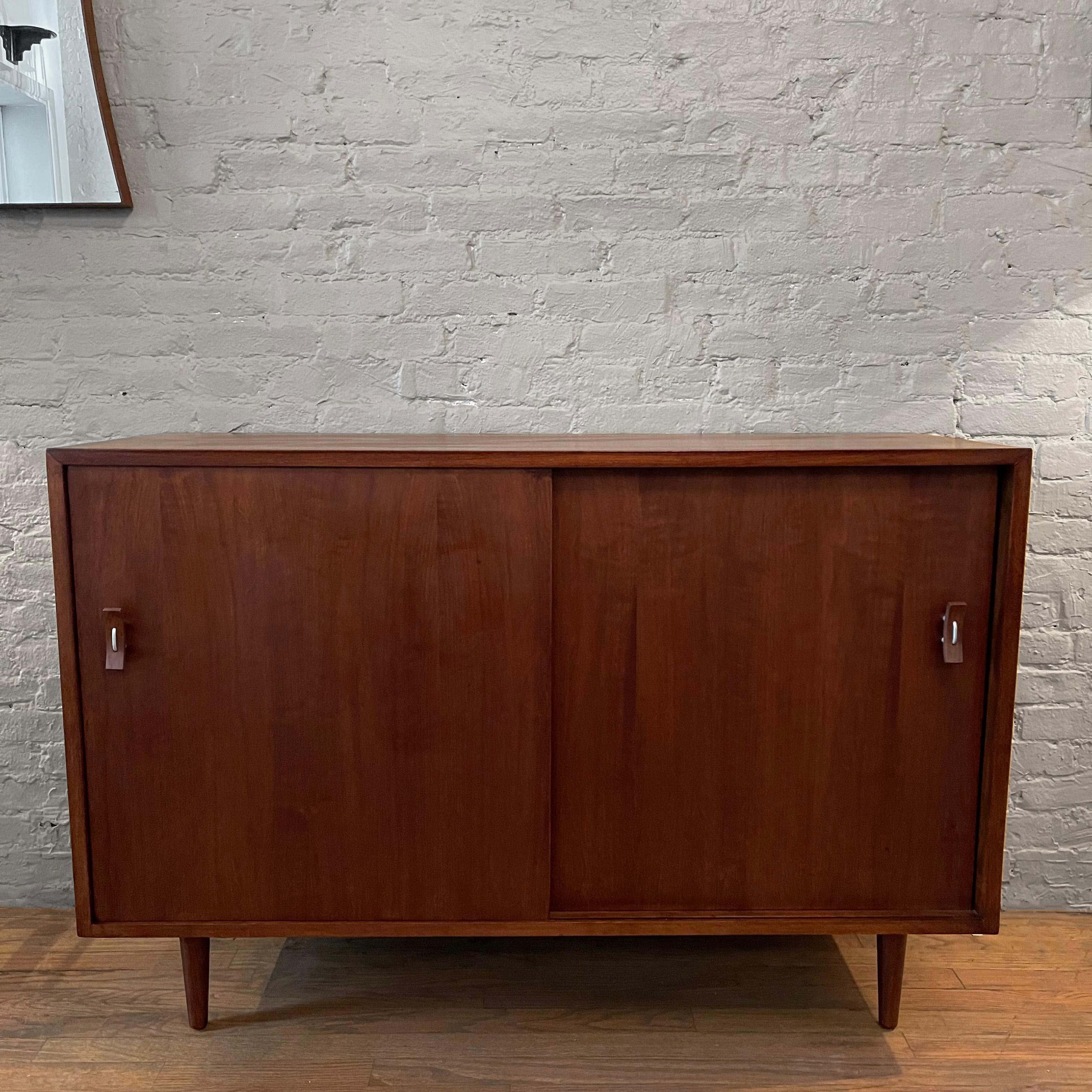 Neatly sized, minimal, mid century modern, walnut credenza by Stanley Young for Glenn Of California features distinctive bentwood and aluminum pulls. Interior storage includes 3 concealed drawers and shelf.