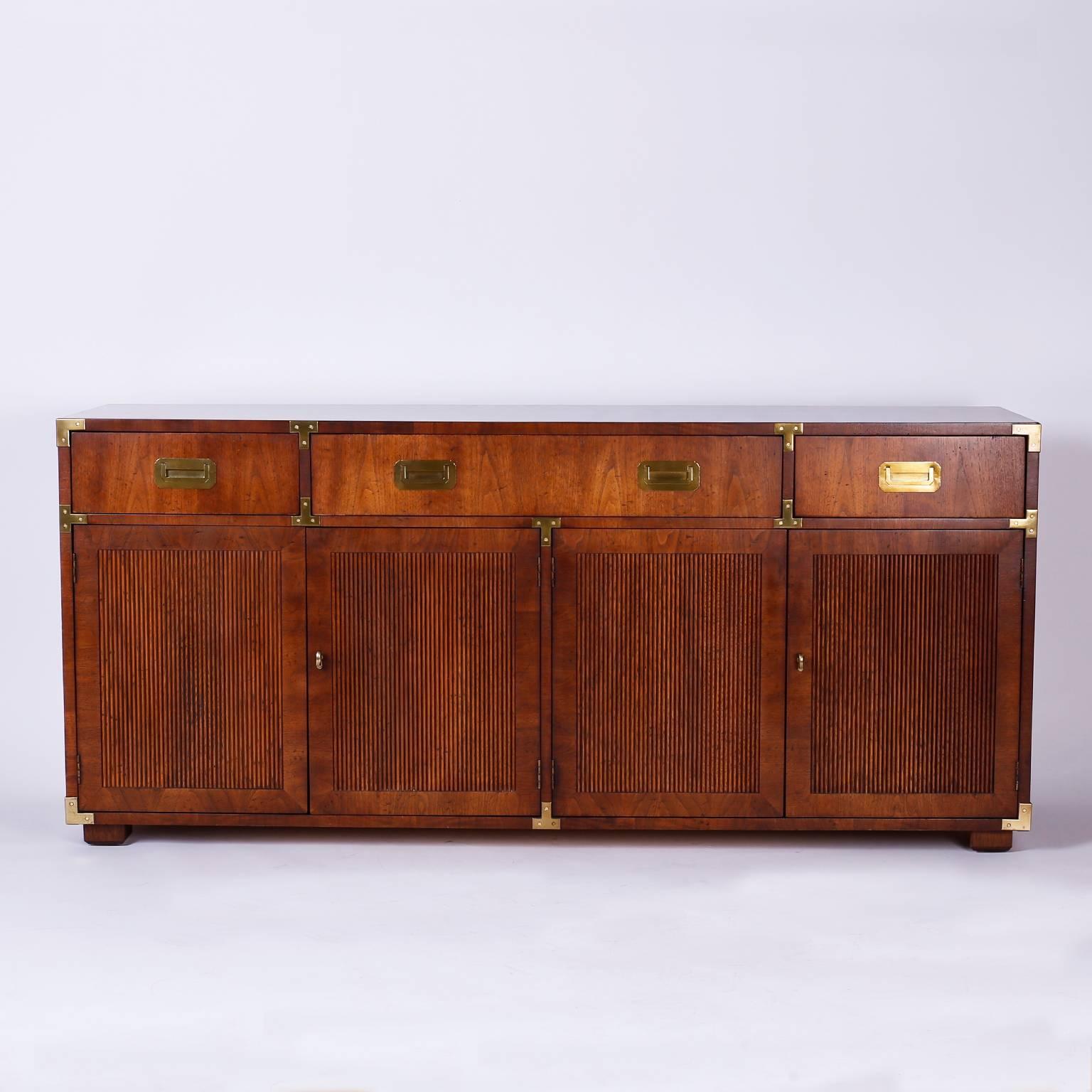 Handsome walnut credenza or sideboard with four beaded doors for
plenty of storage, three drawers above, and polished brass campaign
style hardware which draws on English influence combined with modern form. Branded Henredon in a drawer.