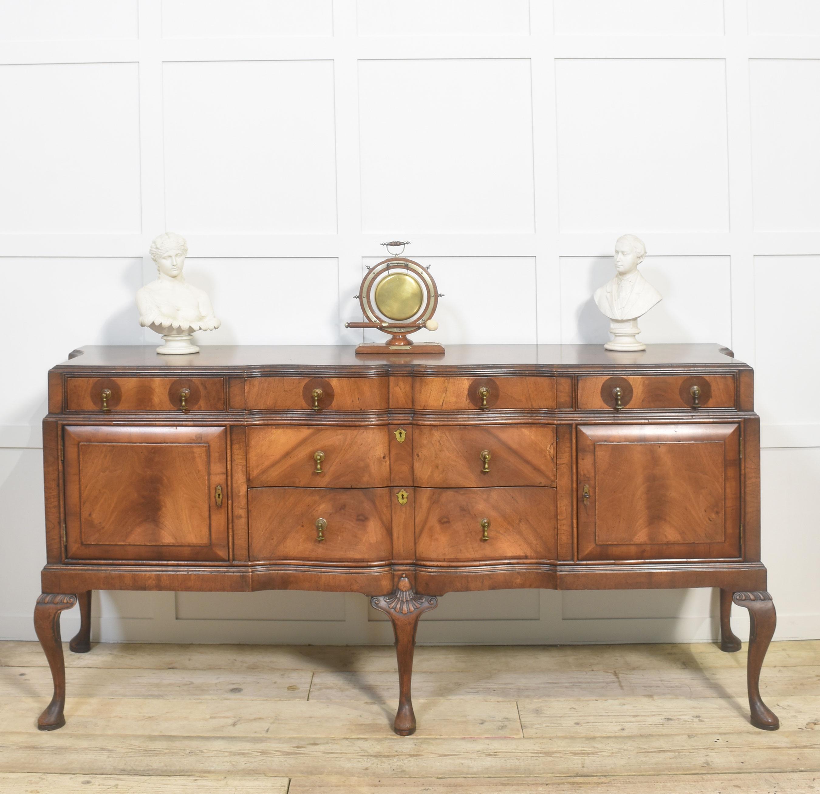 Buffet en noyer de style Queen Ann. Le plateau en forme de bande transversale avec des extrémités concaves. Au congélateur équipé de deux tiroirs courts et d'un tiroir long. Deux portes de placard superposées flanquées de deux tiroirs. Tous sont