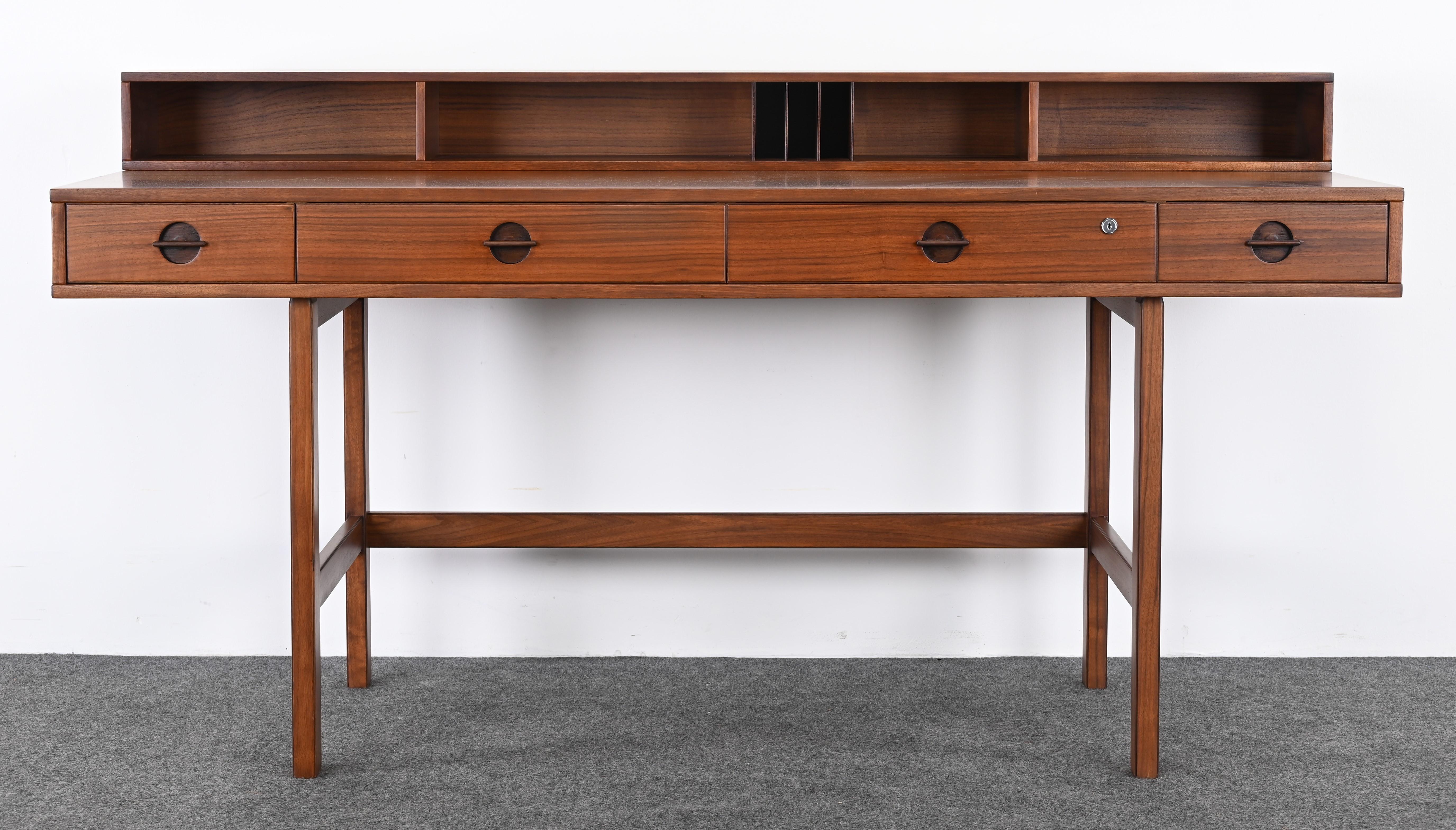 A beautiful expandable Danish Modern walnut desk with a flip-top design by Jens Quistgaard for Peter Lovig Nielsen. This desk can be used either flipped down for expansive space or flipped up for ample storage. Solid walnut construction with a