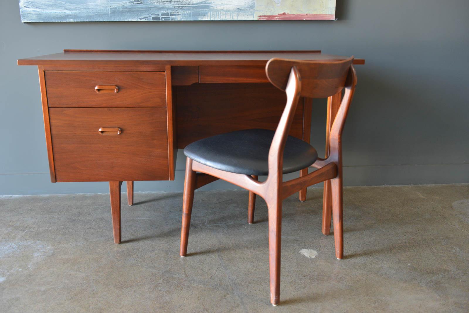 Walnut desk by Jack Cartwright for Founders, circa 1960. Beautiful walnut grain, professionally restored in perfect condition with hidden upper small drawer and two left drawers. Finished on the reverse, the desk can float in a room. Raised back