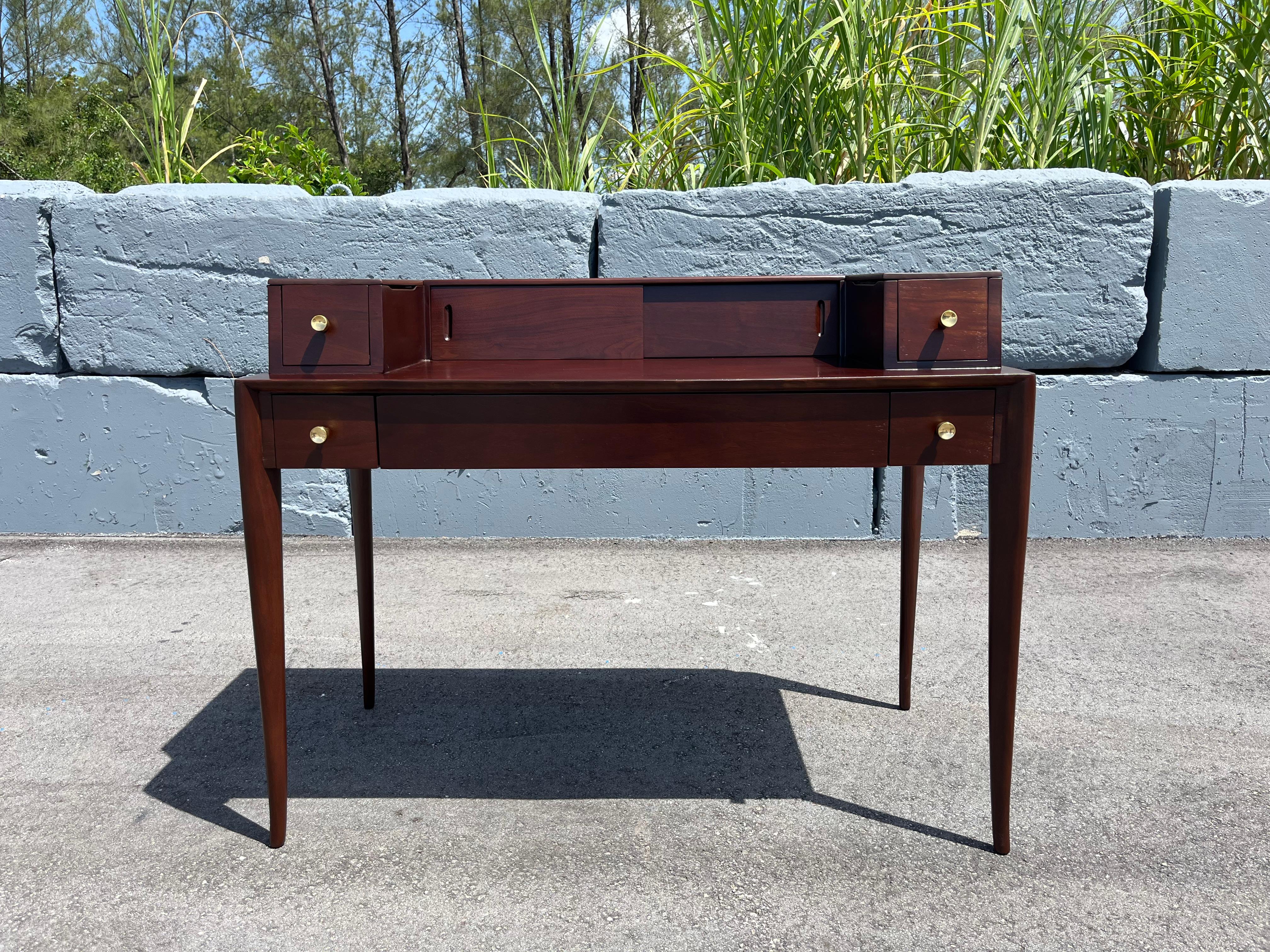 1960s Walnut Desk by T.H.Robsjohn-Gibbings for Widdicomb. 
The desk has one center drawer and four side drawers with brass pulls and extra storage behind two sliding doors. Writing surface height is 29.75