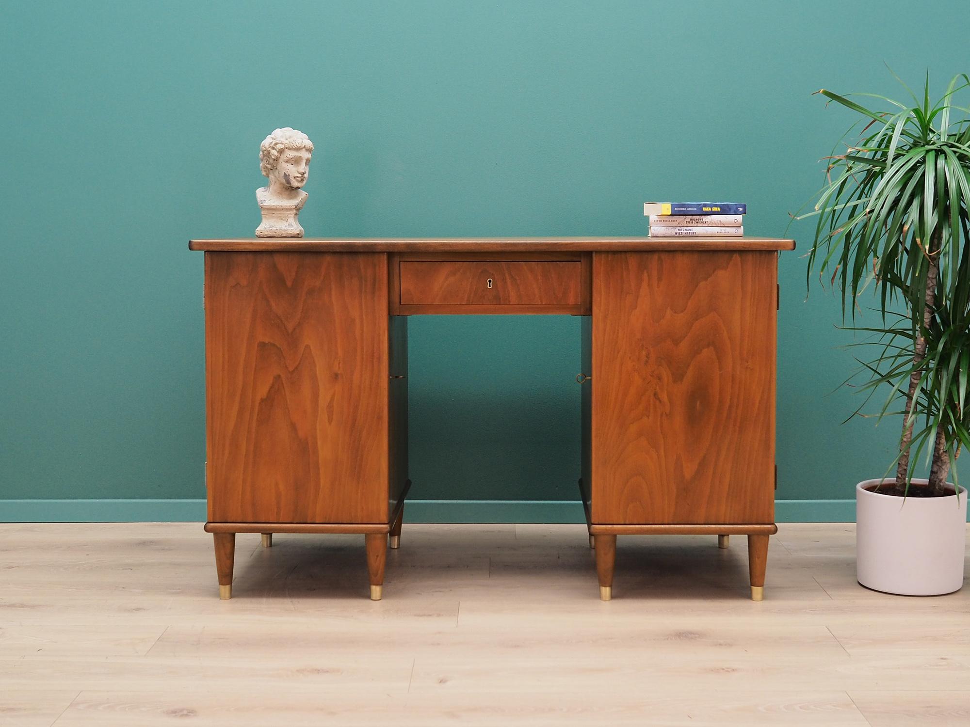 Desk made in the 1960s, Danish production.

Structure and top are covered with walnut veneer. Legs are made of solid walnut wood, perfectly integrated into the structure of the desk. The surface after refreshing. From the front, the desk has one