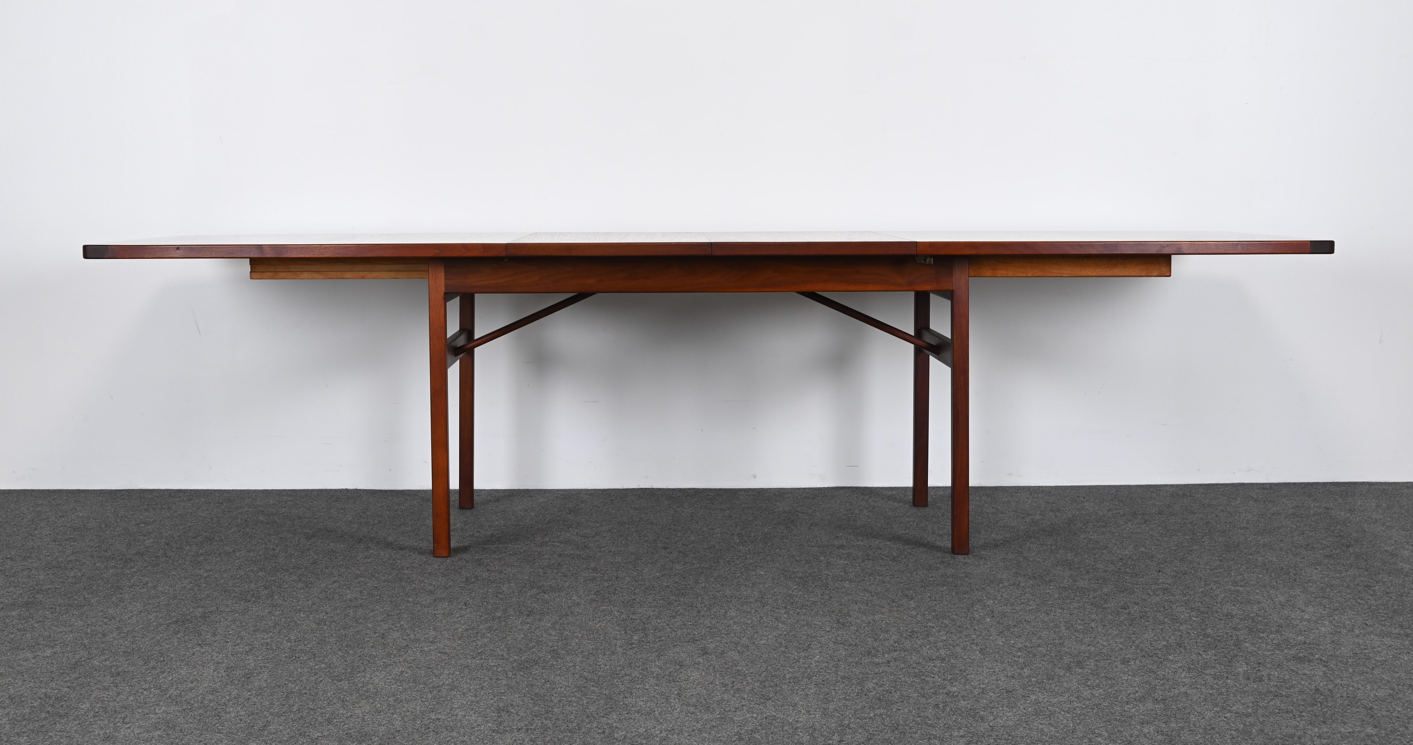 A simple line modern boat top dining table designed by Jens Risom circa 1950. The table has two leaves and extends to 112 inches. The Danish Modern style table retains its original finish. The leaves of the table are slightly lighter but overall not