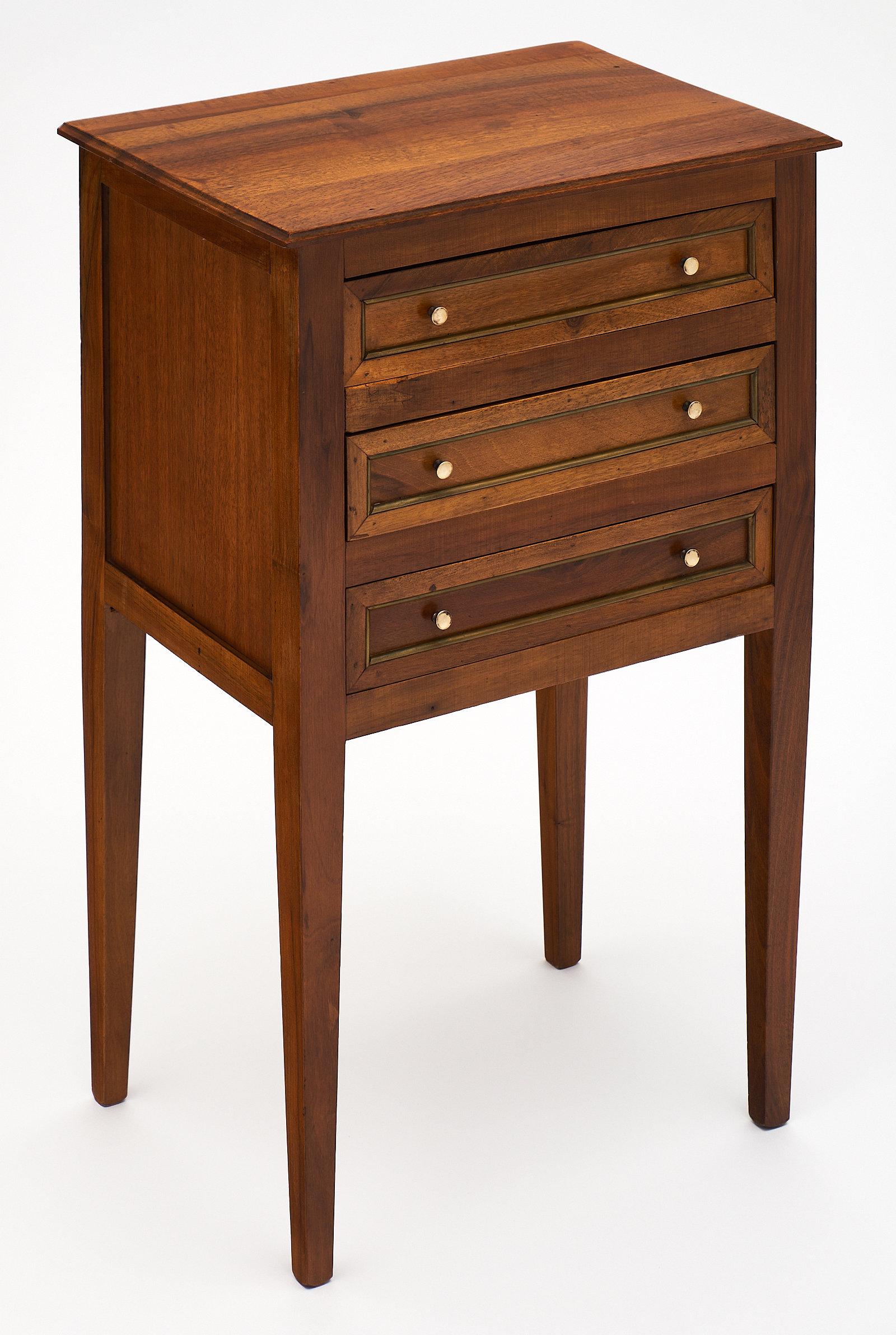 Charming Directoire style walnut side table. This antique French piece features three dovetailed drawers and brass pulls. We love the Classic proportions with the Provincial flair. The tapered legs bring elegance!