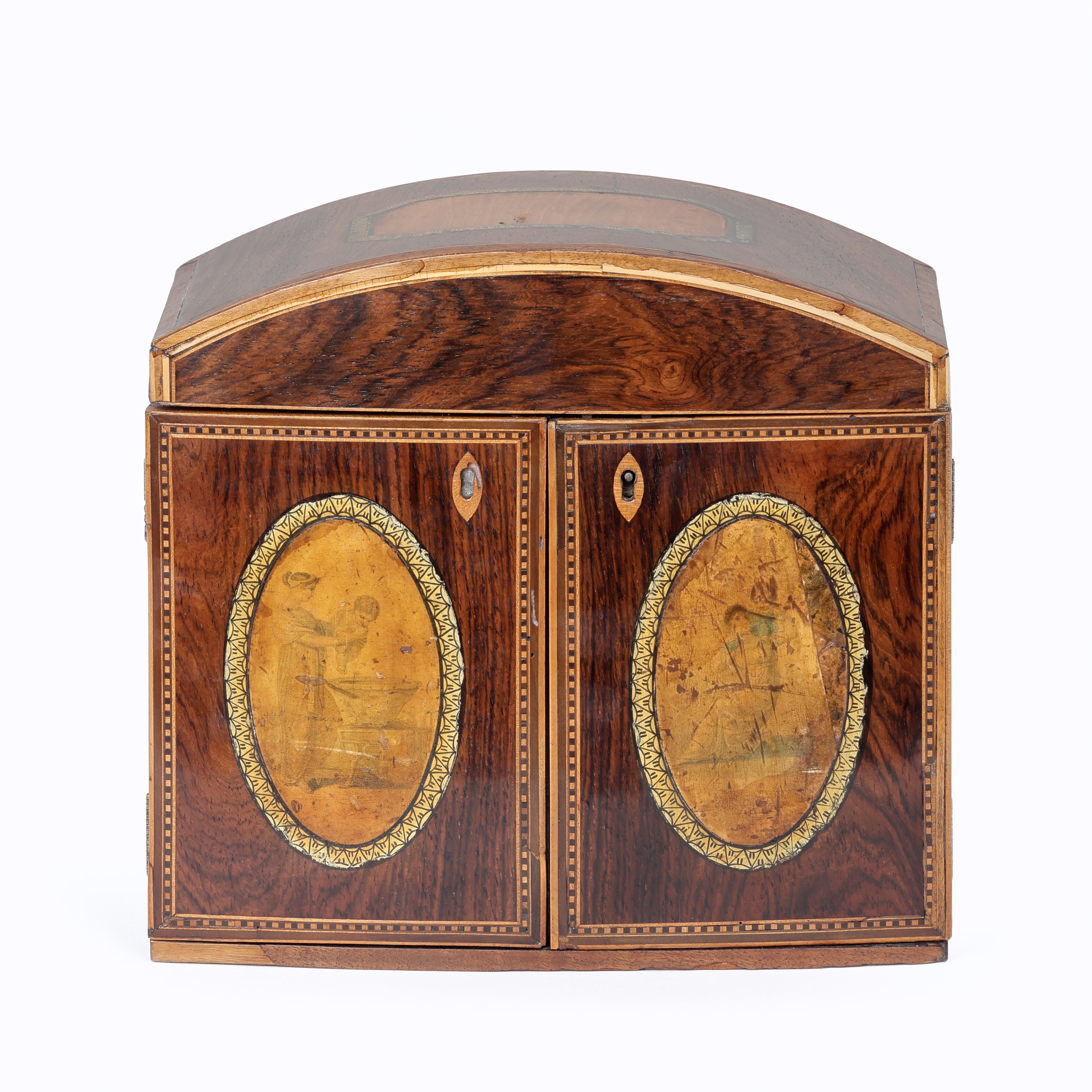 An early 19th century walnut domed topped needlework or jewellery box with two doors enclosing three drawers.  Decorated with a panel of satinwood in the top and two penwork sketches to the oval inlaid panels in the doors.
