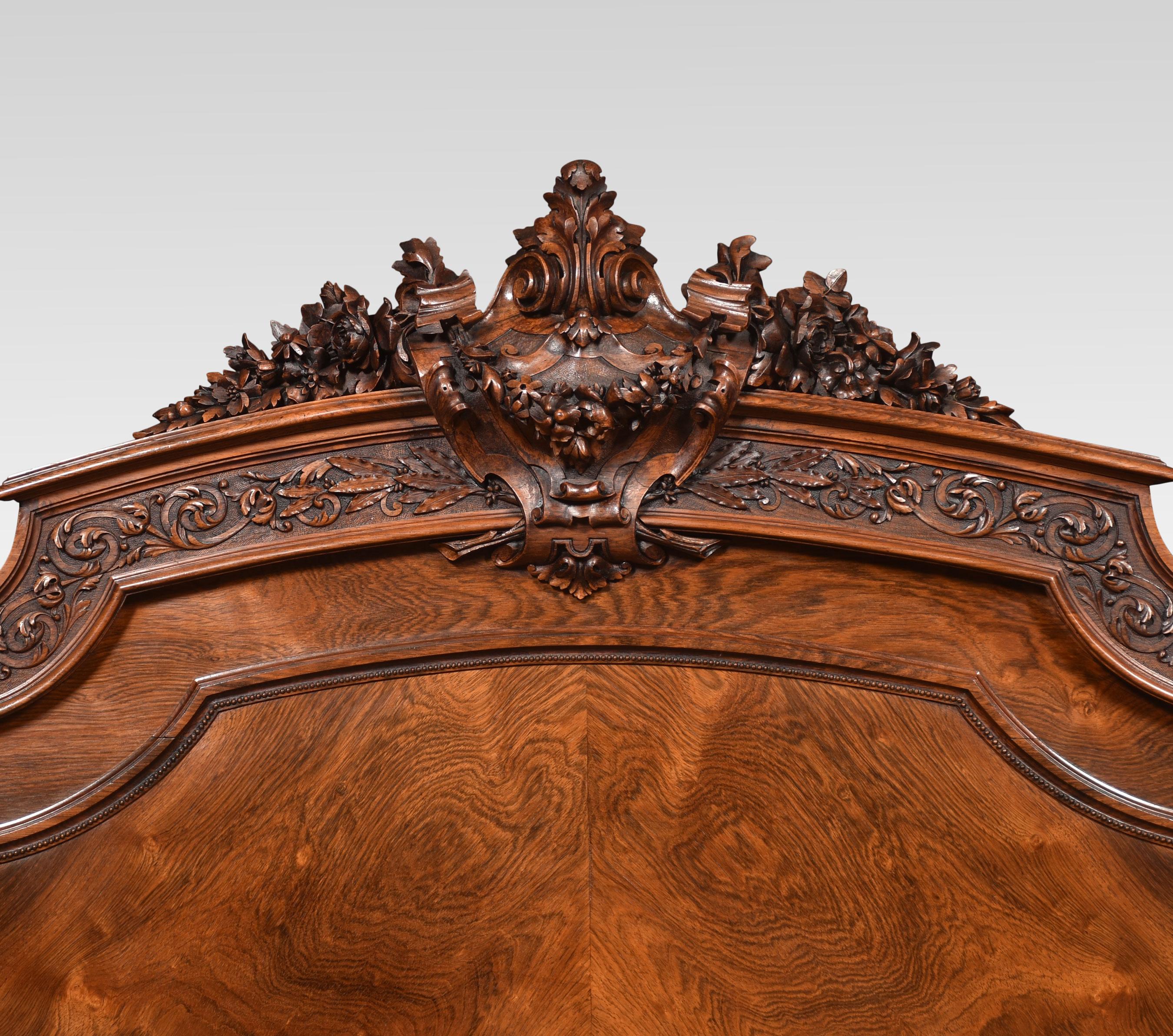 French-style walnut and rosewood double bed the ornately carved headboard flanked by reeded columns with urn capitals. To the side rails with scrolling and swag detail. The footboard with exceptional central carved panels flanked by reeded columns
