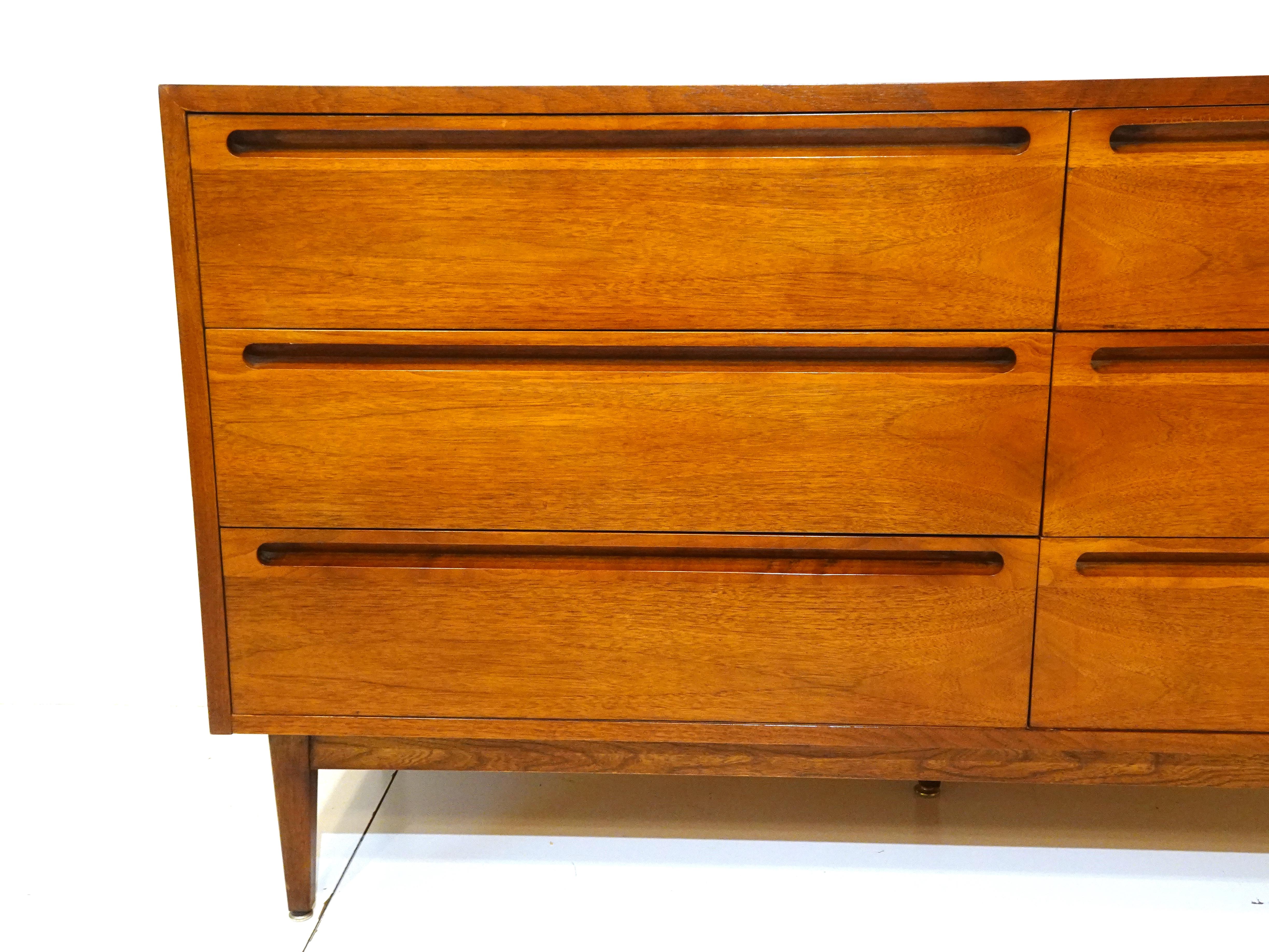 A medium dark walnut six drawer dresser chest with inset cut pulls to the top edge of each drawer giving the piece a clean look. Having plenty of storage to each drawer it's the perfect mid century piece for organizing, a rare form manufactured by