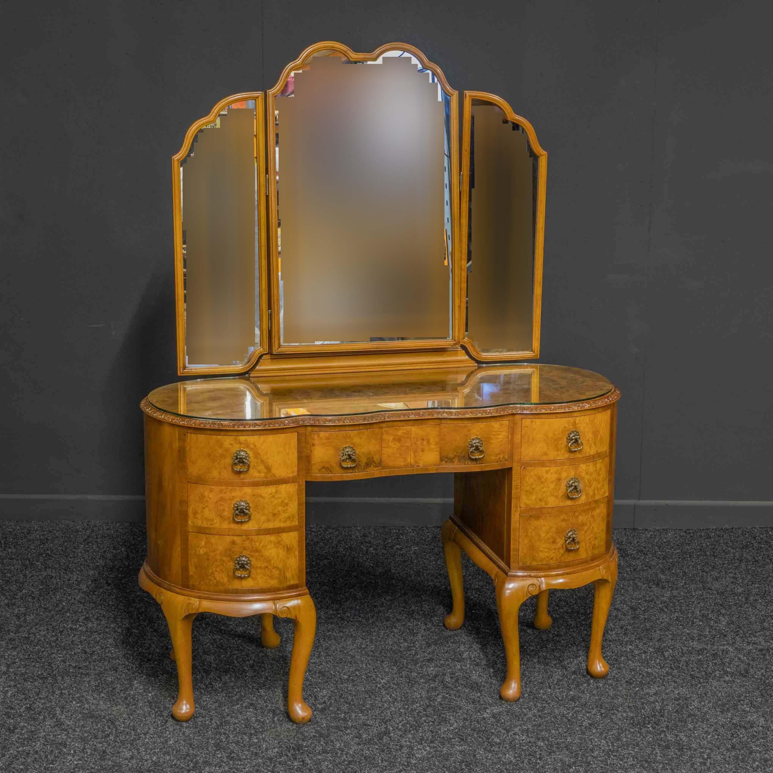 A very attractive walnut veneered dressing table with a very shapely design. Although of delicate appearance it is very sturdy, with eight legs in total. All the original cast brass drop handles are present and the drawers run smoothly. The triple