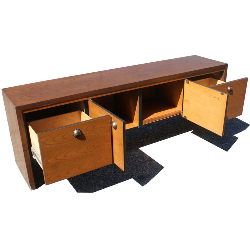 A mid century modern credenza made by Dunbar.  Nicely figured continuous walnut graining on front doors and brass pulls.